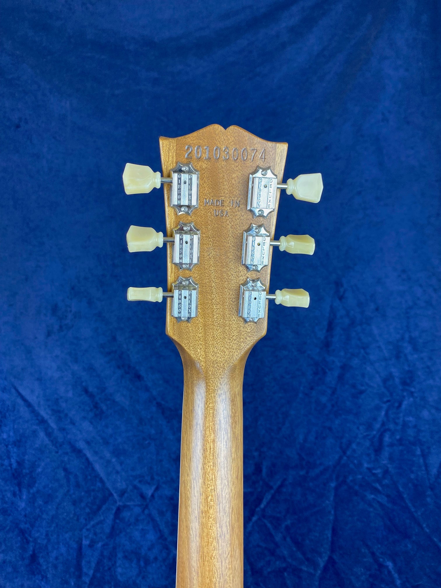 Back of an electric guitar headstock with six vintage-style tuners, serial number 201030074, and "Made in USA" stamped on the wood.