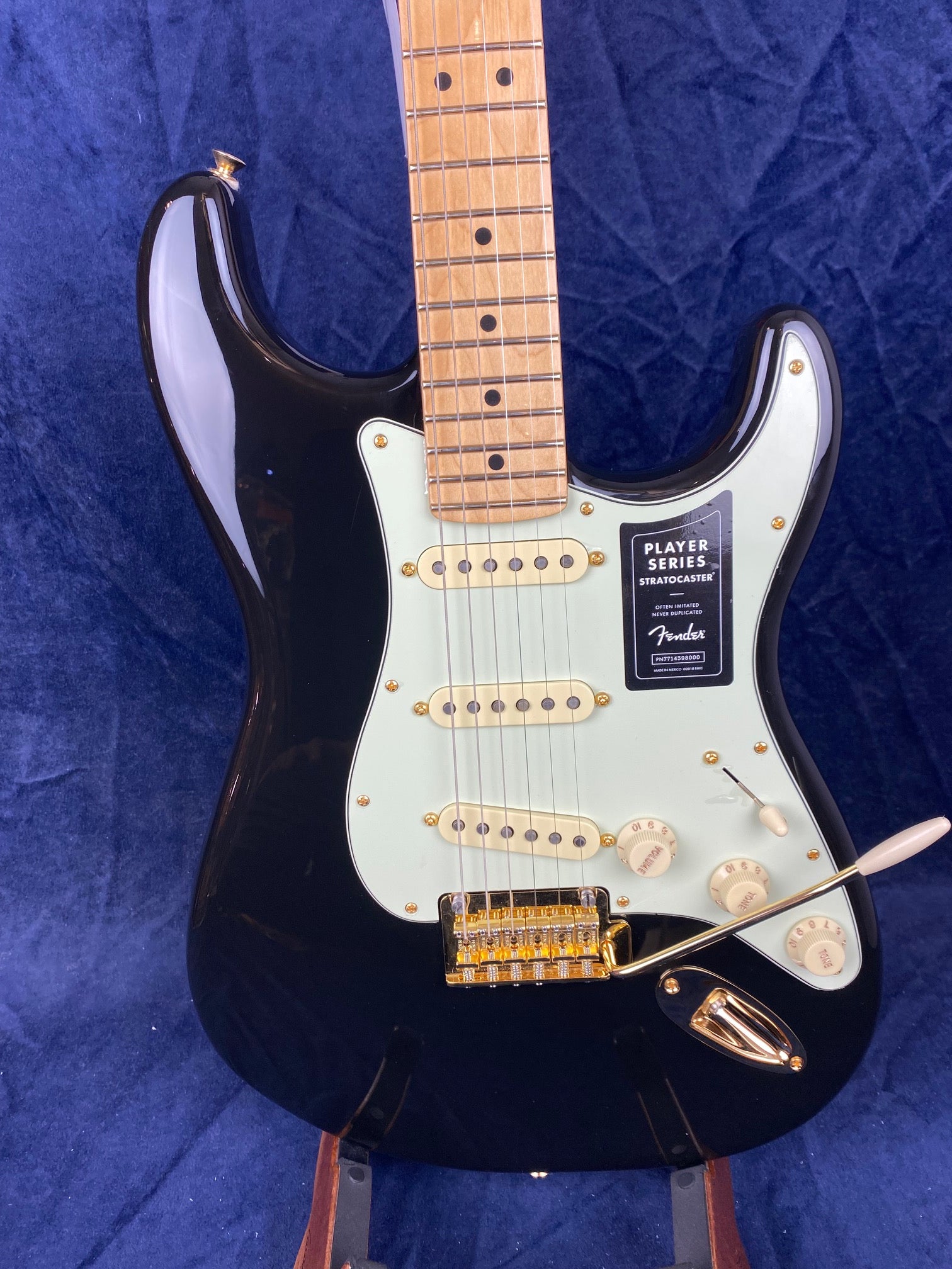 Fender Player Series Stratocaster electric guitar in black with a white pickguard, maple neck, three single-coil pickups, and gold hardware.