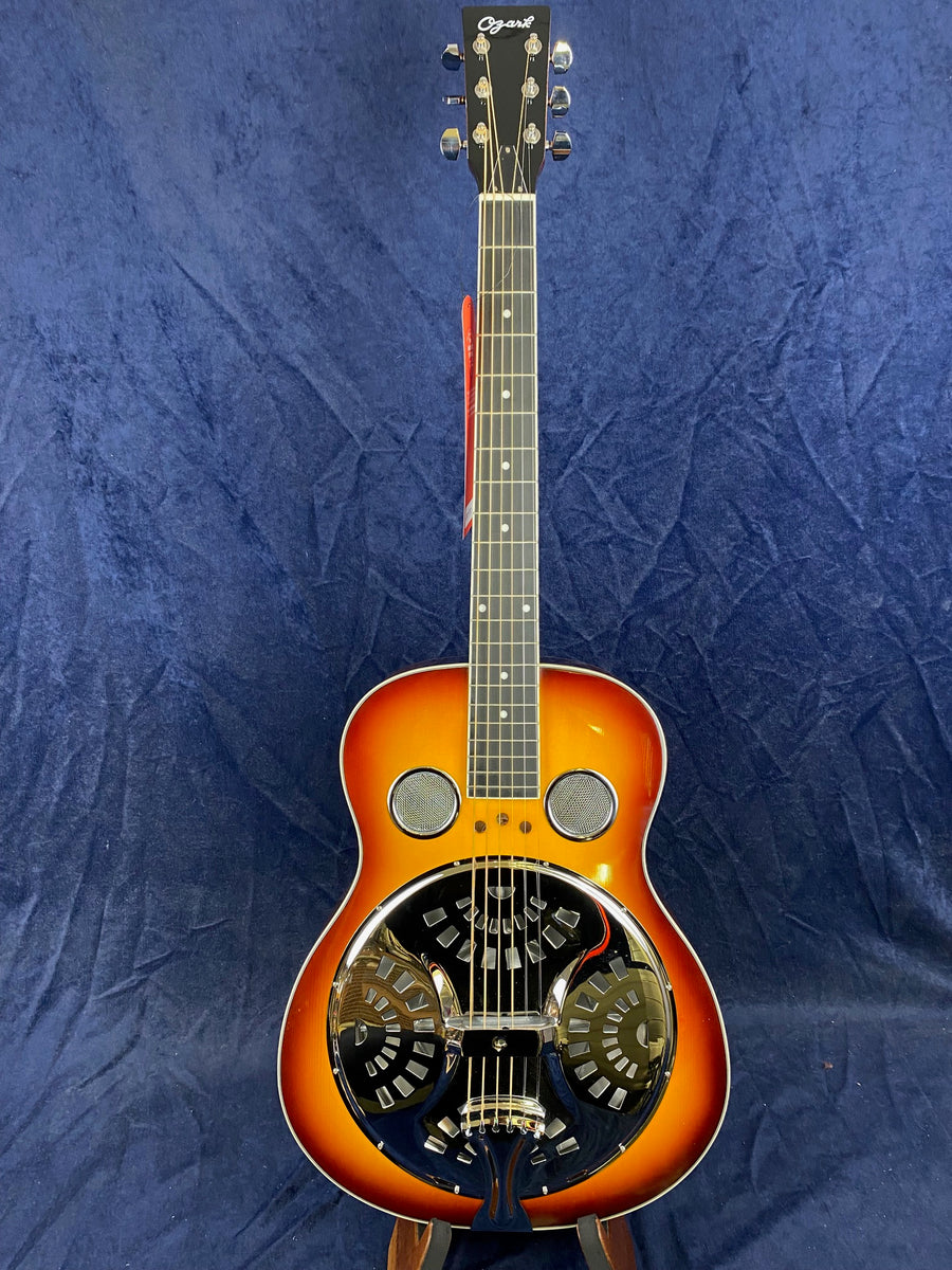 Sunburst resonator guitar with circular metal resonator plate and two round sound holes near the fretboard. The headstock shows the brand name Ozark.