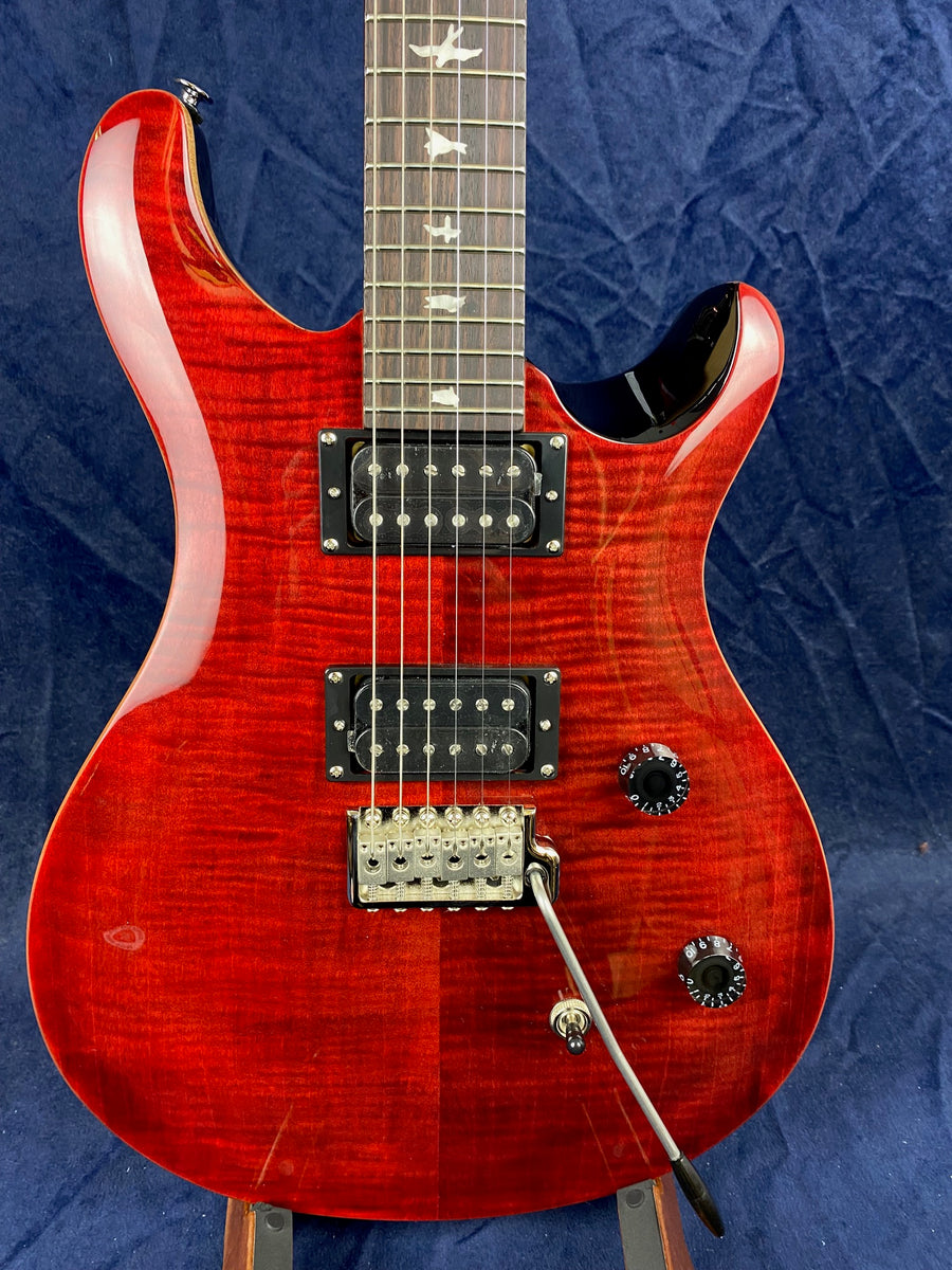 Red electric guitar with a glossy, flamed wood finish, two black humbucker pickups, bird inlays on the fretboard, and a whammy bar.
