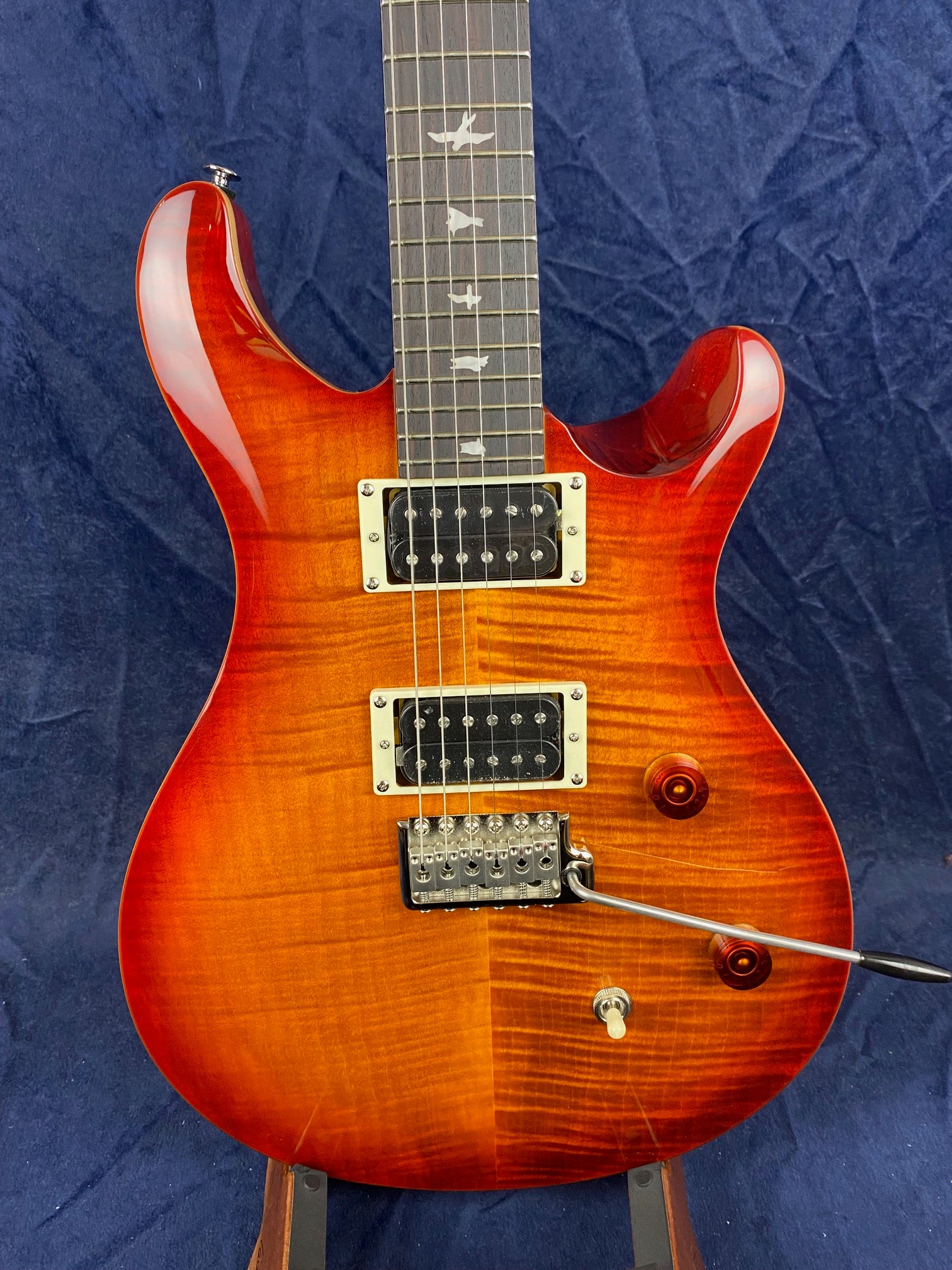 Glossy sunburst electric guitar with two humbucker pickups, bird inlays on the neck, and a tremolo bridge with whammy bar.