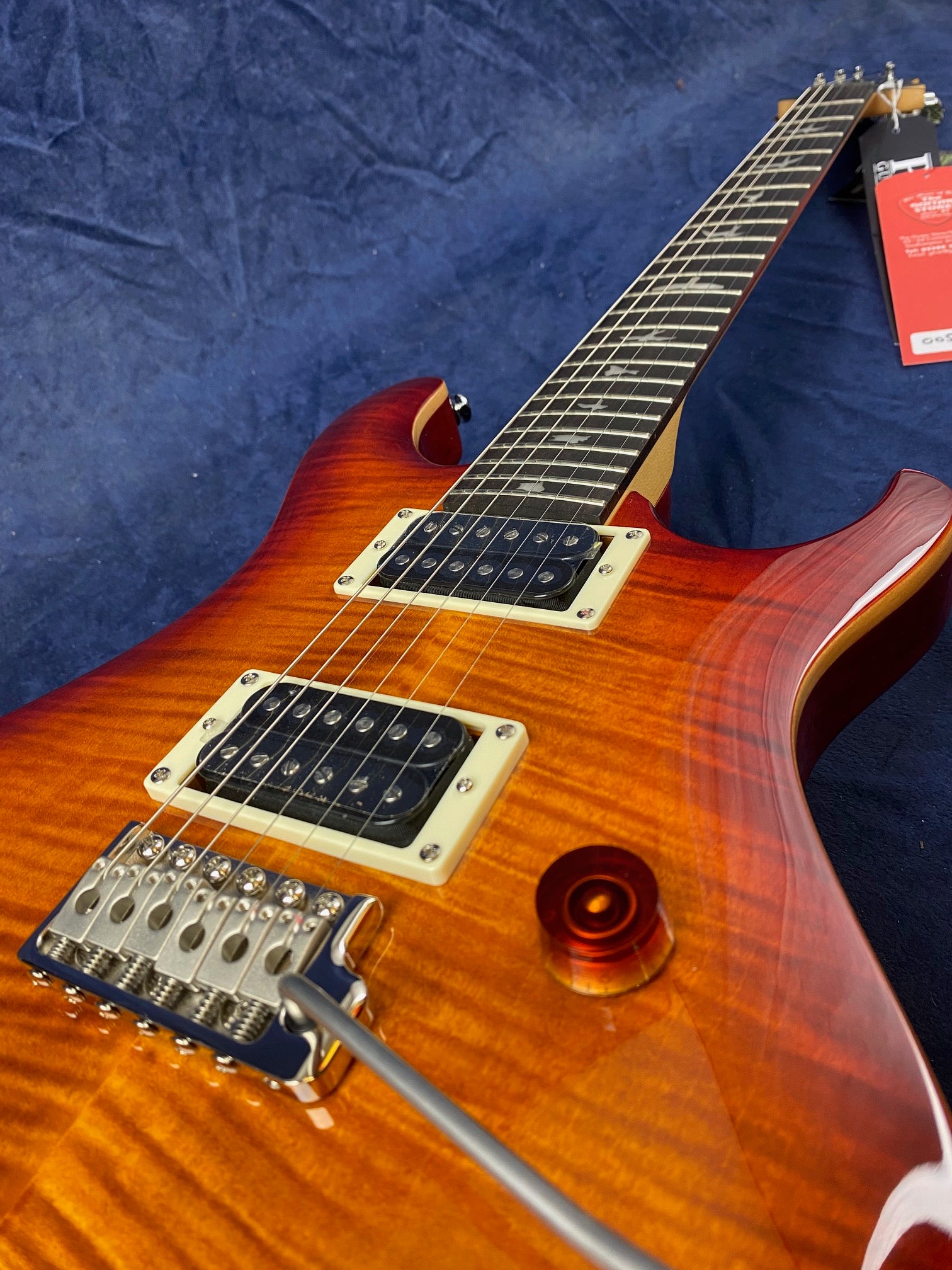 Sunburst electric guitar with dual humbucker pickups, six strings, whammy bar, and a glossy finish on a flamed maple top, viewed from the body upward.