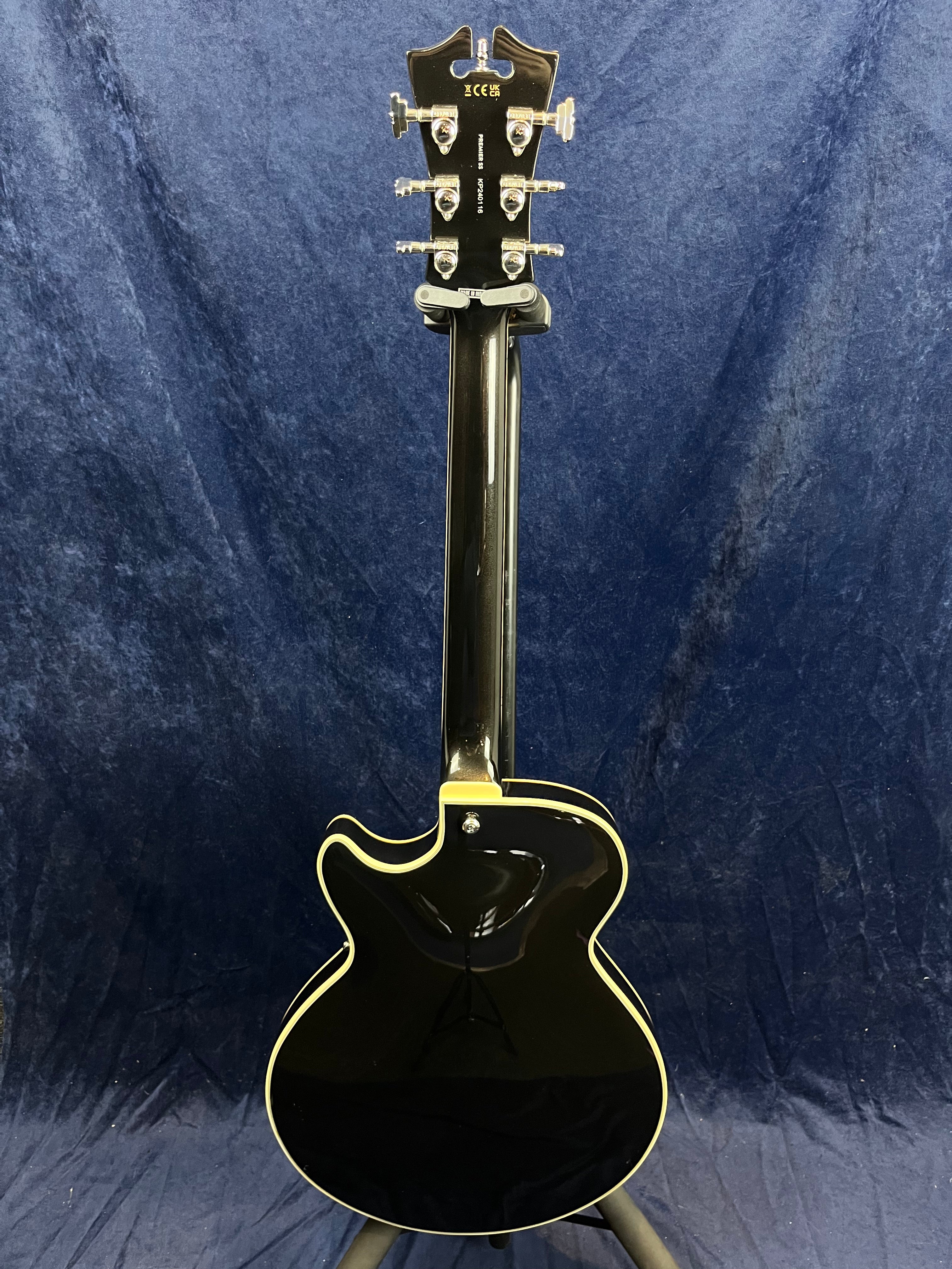 Black electric guitar seen from the back, single cutaway design, cream binding along the edges, and chrome tuning pegs on the headstock.