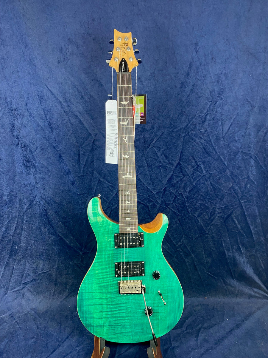 Electric guitar with a bright green body, two black humbucker pickups, a tremolo bridge, and bird inlays on a dark fretboard.