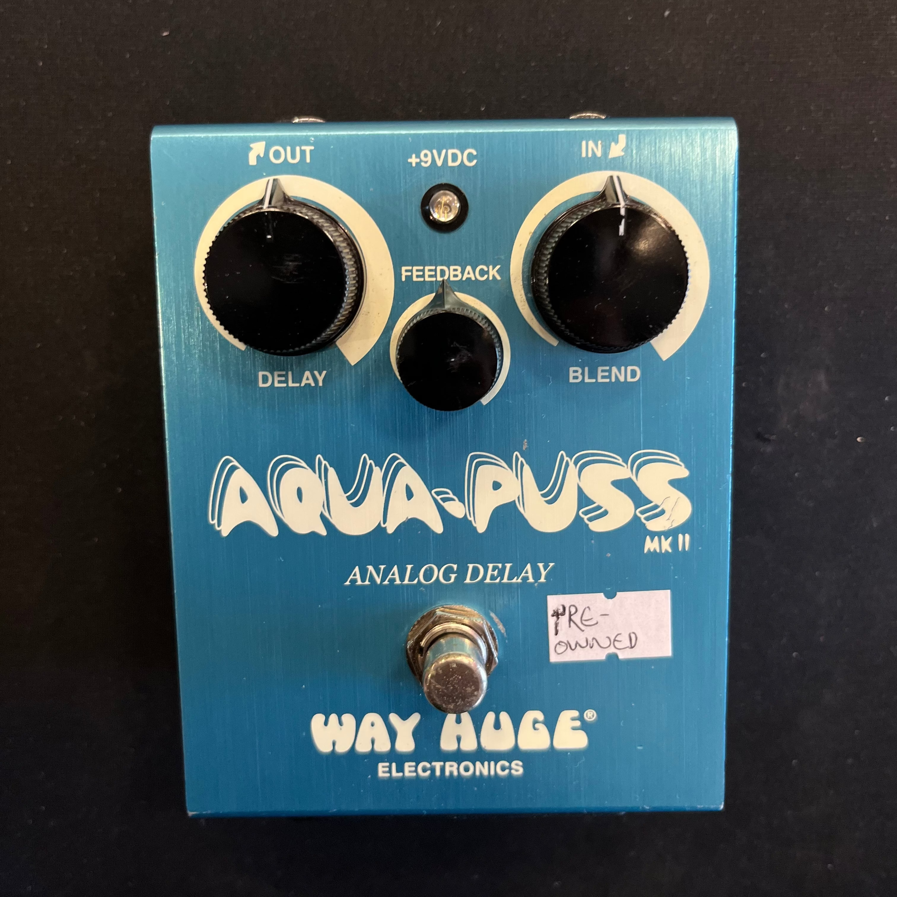 Blue Way Huge Aqua-Puss MKII analog delay guitar effects pedal with three black knobs, labeled as pre-owned, and white decorative text.