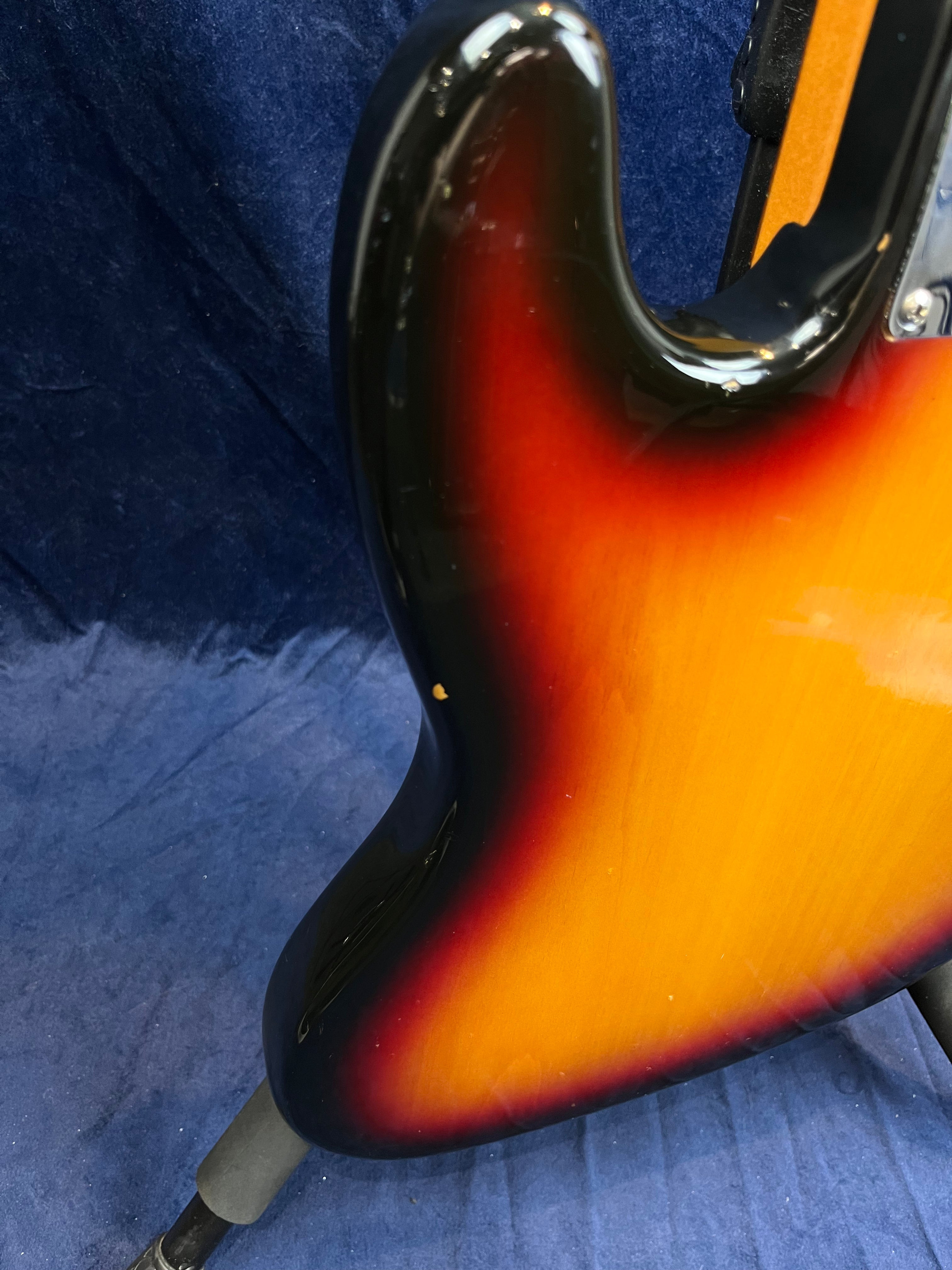 Sunburst finish bass guitar body with black, red, and yellow tones; a small chip in the paint is visible near the lower edge.