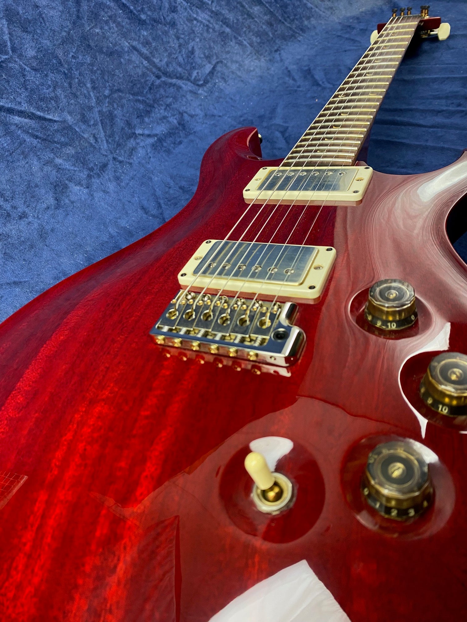 Glossy red electric guitar with gold hardware, two humbucker pickups, four black and gold control knobs, and a three-way cream toggle switch.