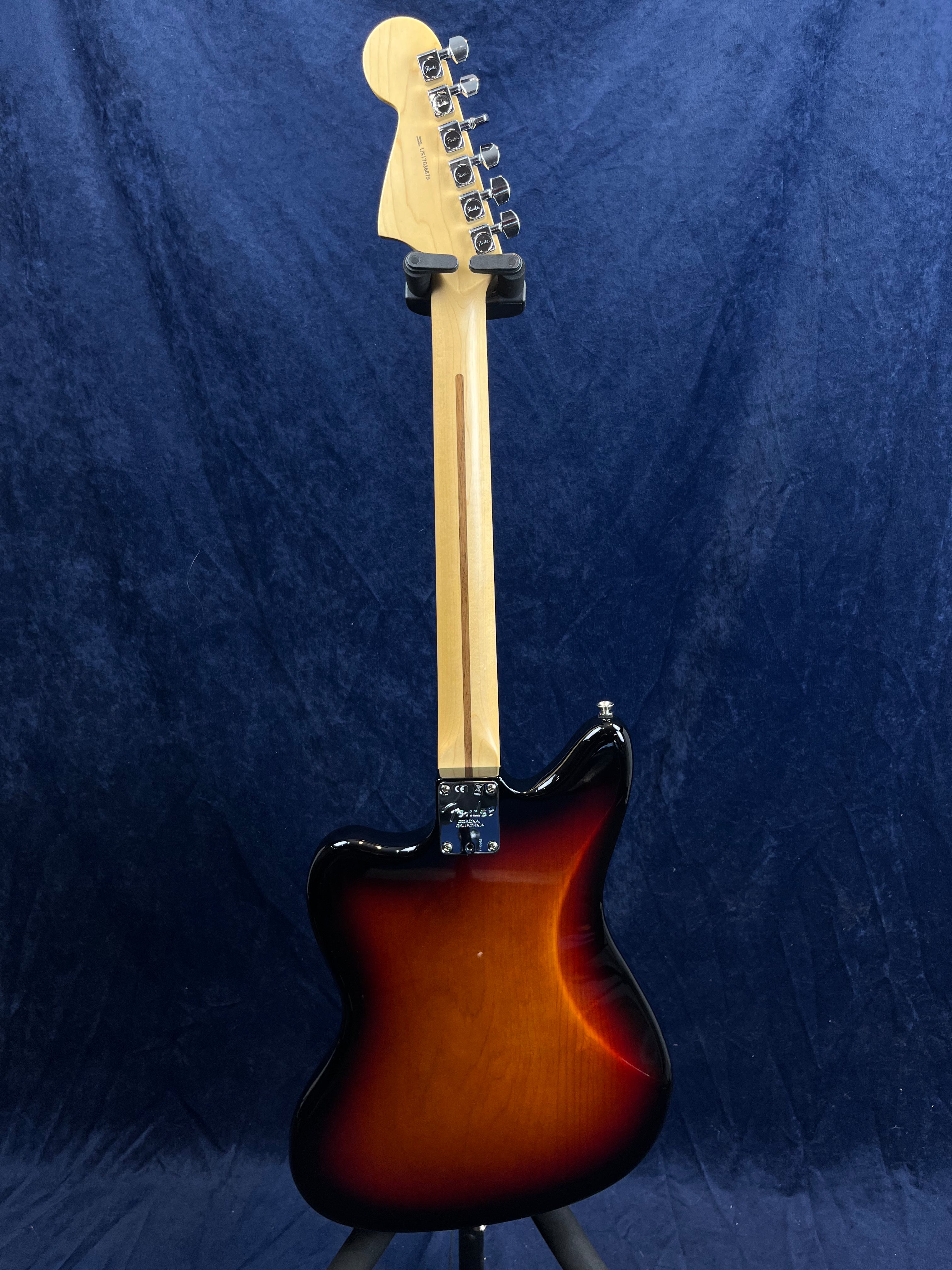 Electric guitar shown from the back, featuring a sunburst finish body, natural wood neck, and six chrome tuning pegs against a dark blue background.