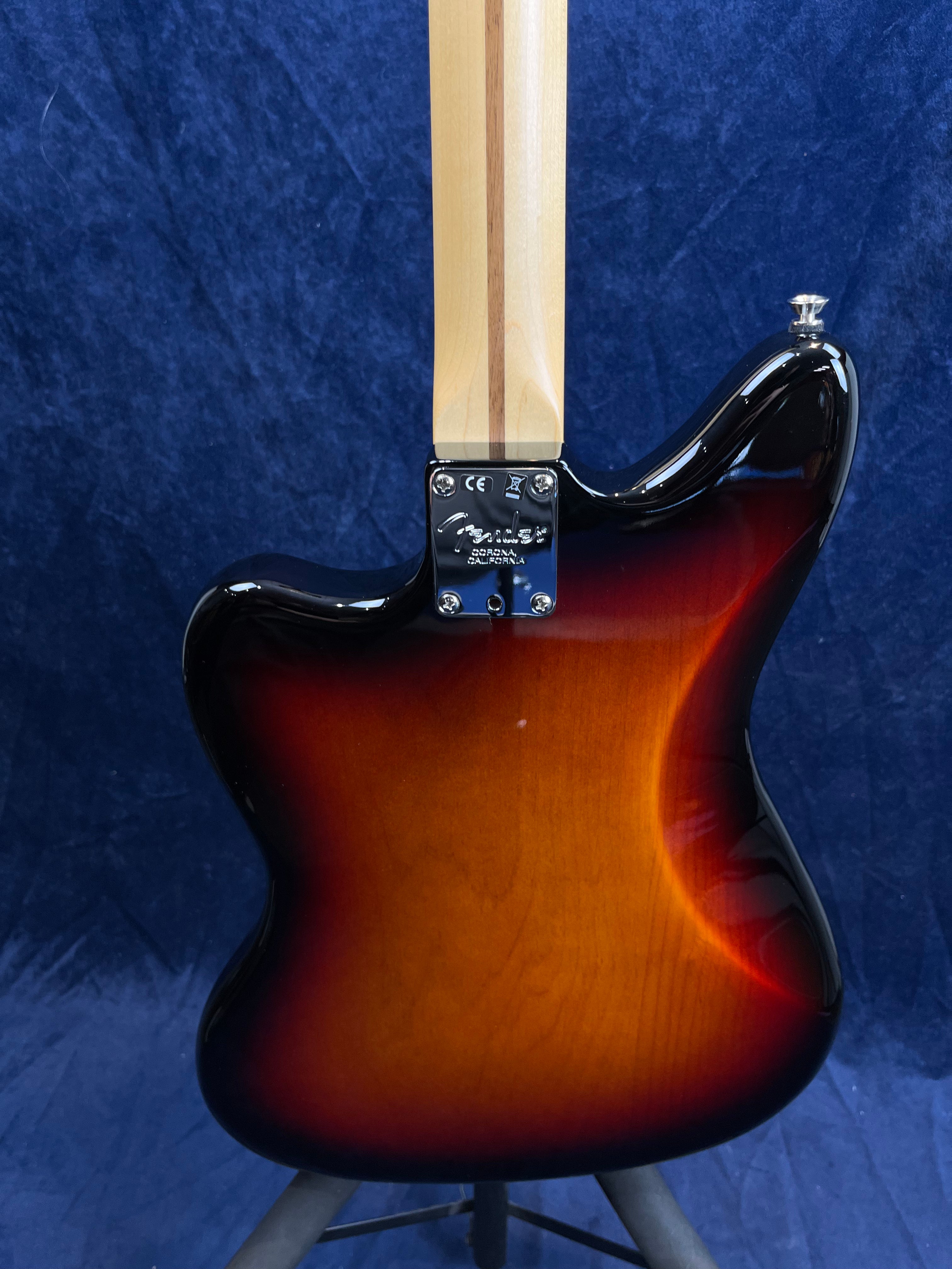 Rear view of an electric guitar with a sunburst finish, natural wood neck, and chrome neck plate engraved with "Fender Corona, California."