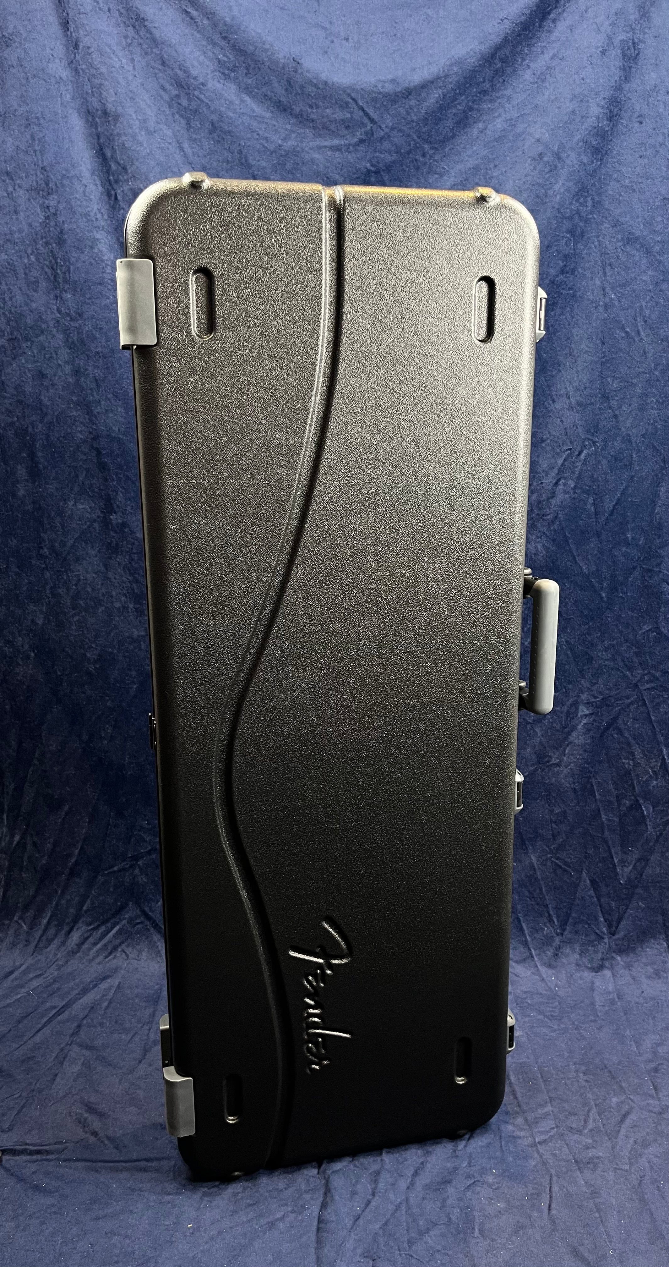Hard black textured Fender electric guitar case, rectangular with rounded corners, molded handle, and an embossed Fender logo on the front.