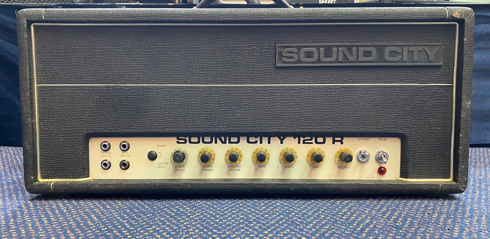 Sound City 120R amplifier head in black tolex with silver control panel, nine yellow knobs, four input jacks, and two toggle switches.