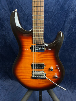 Electric guitar with a sunburst finish, dual humbucker pickups, two control knobs, a pickup selector switch, and a whammy bar on a dark blue background.