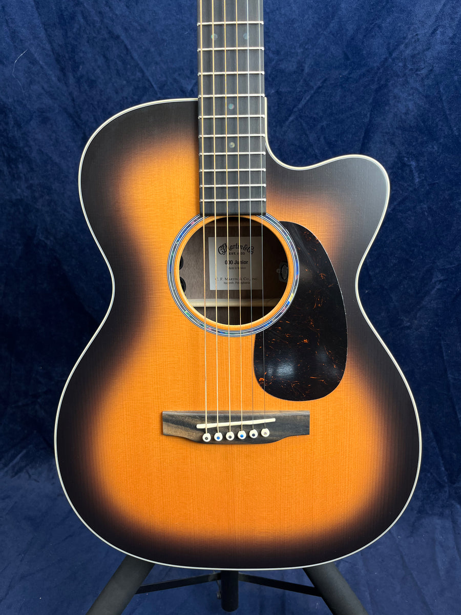 Guitare acoustique Martin à pan coupé, finition sunburst dégradé du noir vers l’orange, six cordes, pickguard noir marbré.