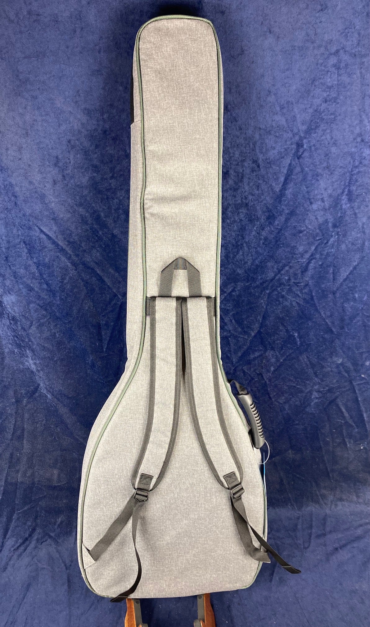 Light gray soft case with backpack straps, sized for a banjo, shown upright against a dark blue background.