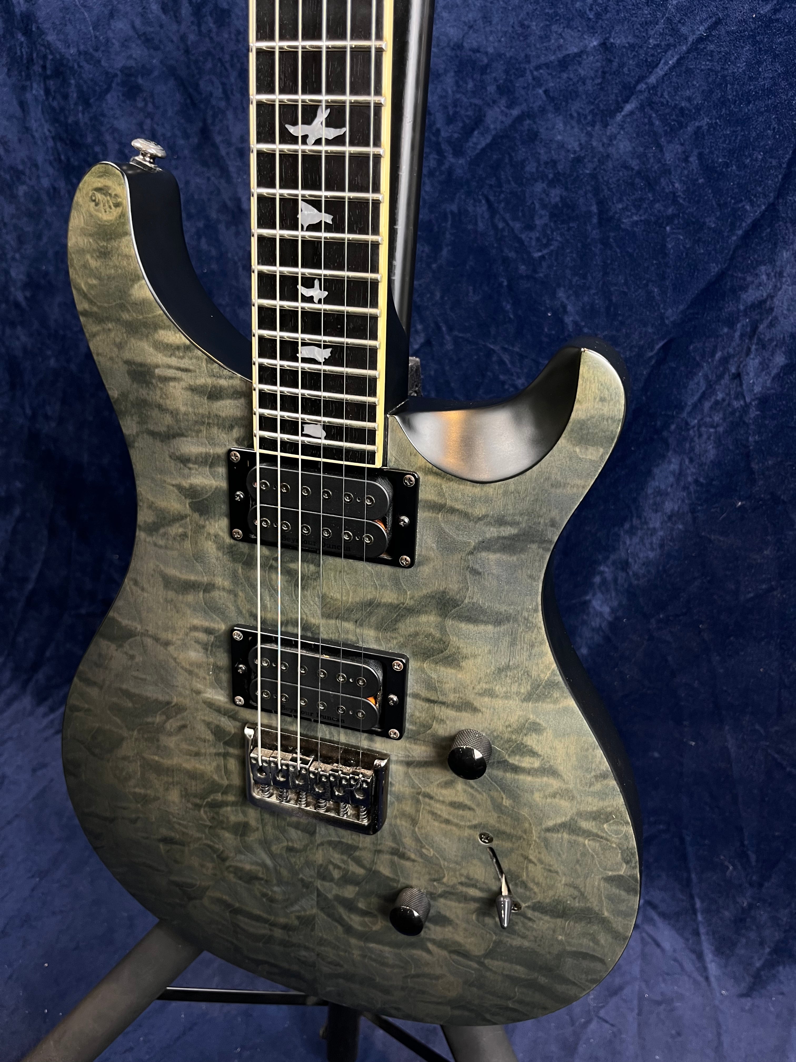 Electric guitar with a quilted gray finish, two humbucker pickups, two control knobs, a switch, and bird inlays on a dark fretboard.