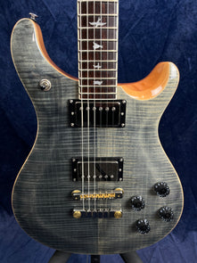 Electric guitar with a gray flame maple top, two black humbucker pickups, four black control knobs, and fretboard with bird inlays.