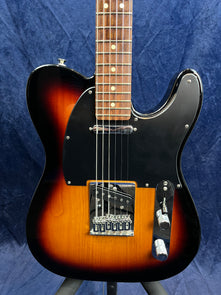 Sunburst electric guitar with a black pickguard, two control knobs, and six strings, shown from the body up to the lower neck.