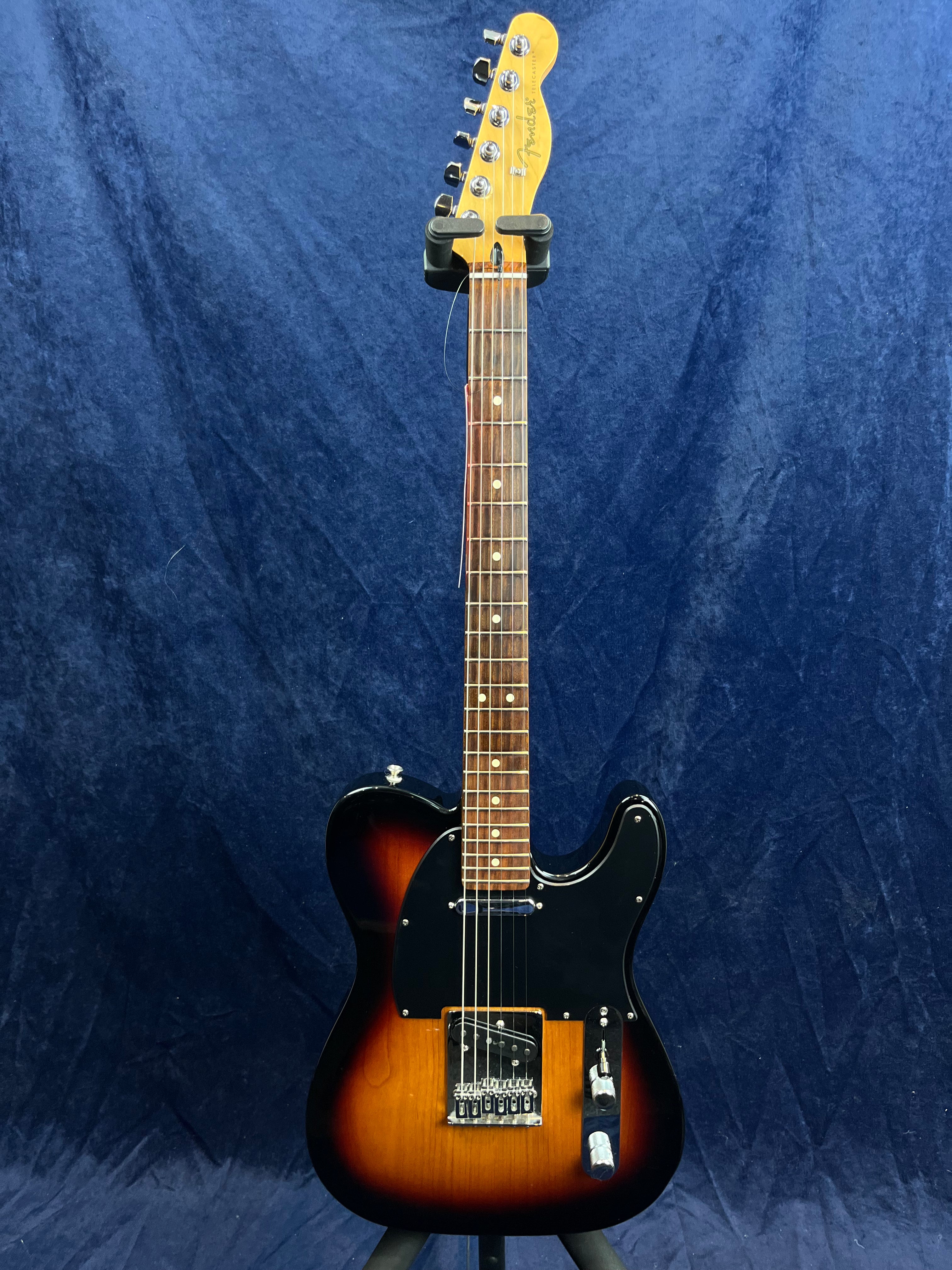 Guitare électrique de style Telecaster avec corps noir et marron sunburst, plaque pickguard noire et manche en bois clair avec repères blancs.