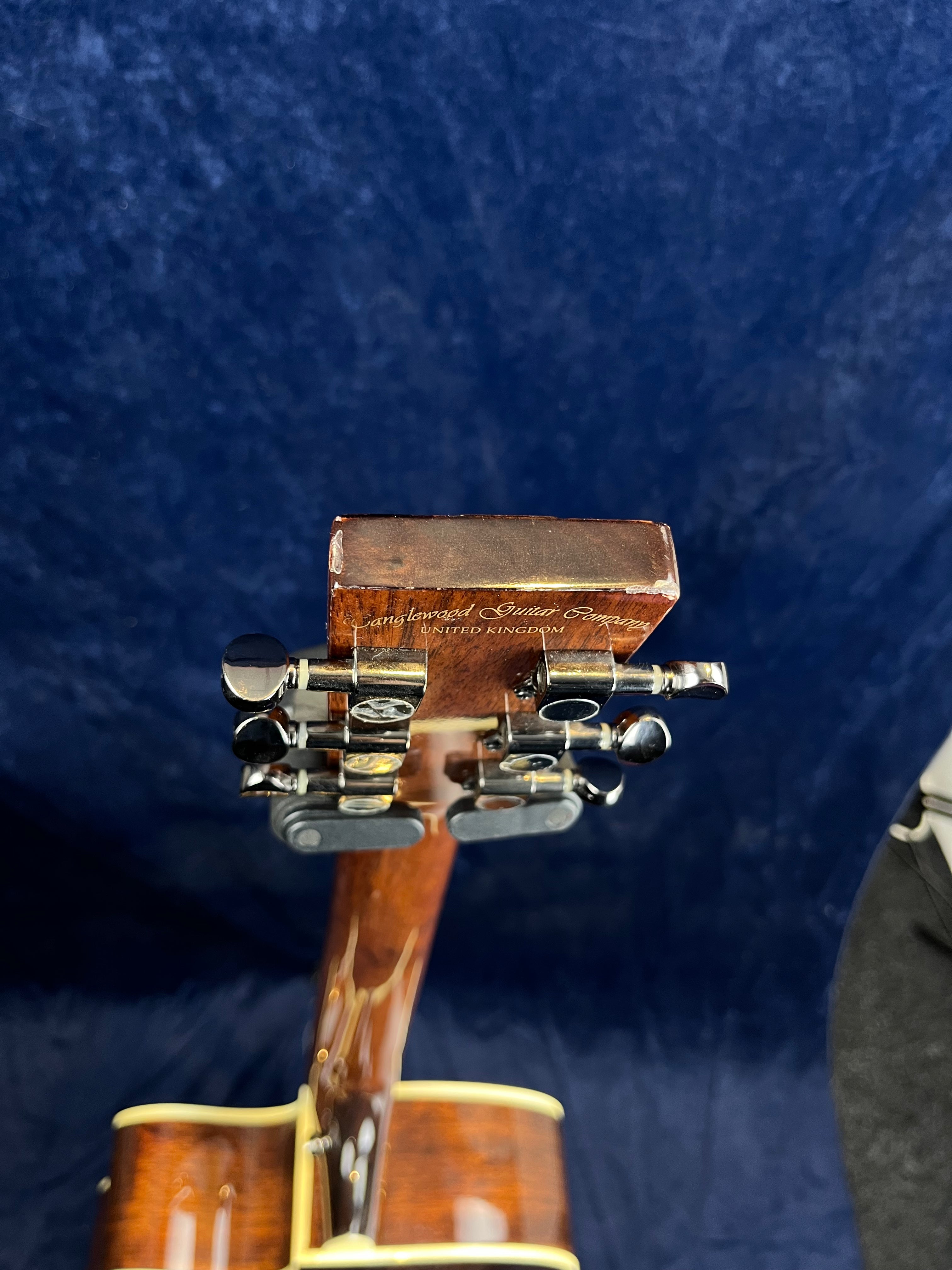 Brown acoustic guitar neck with six chrome tuning pegs, yellow binding, and "Tanglewood Guitar Company United Kingdom" engraved on the headstock.
