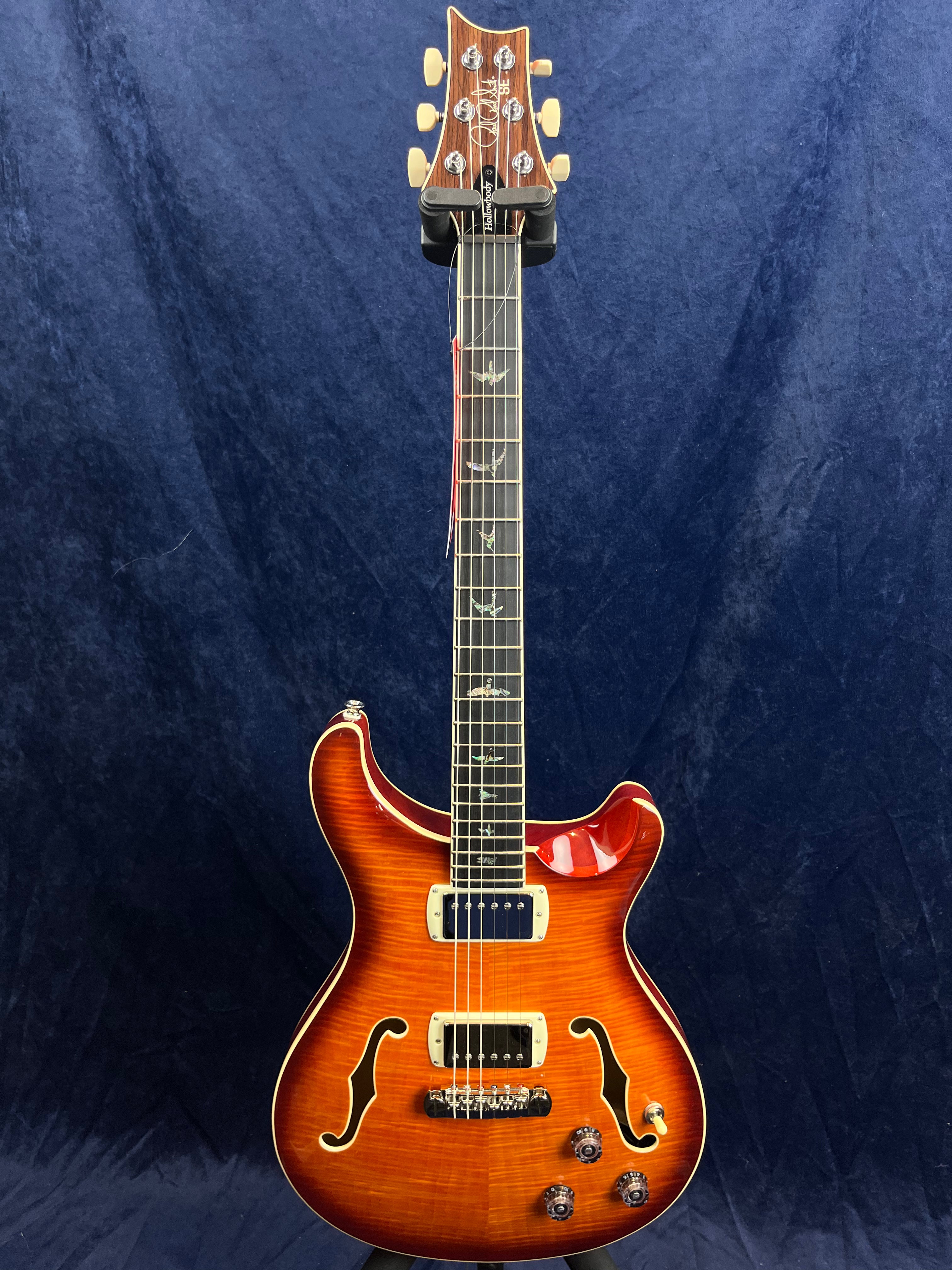 Cherry sunburst electric guitar with two f-holes, two humbucker pickups, four control knobs, and bird inlays on the fretboard.