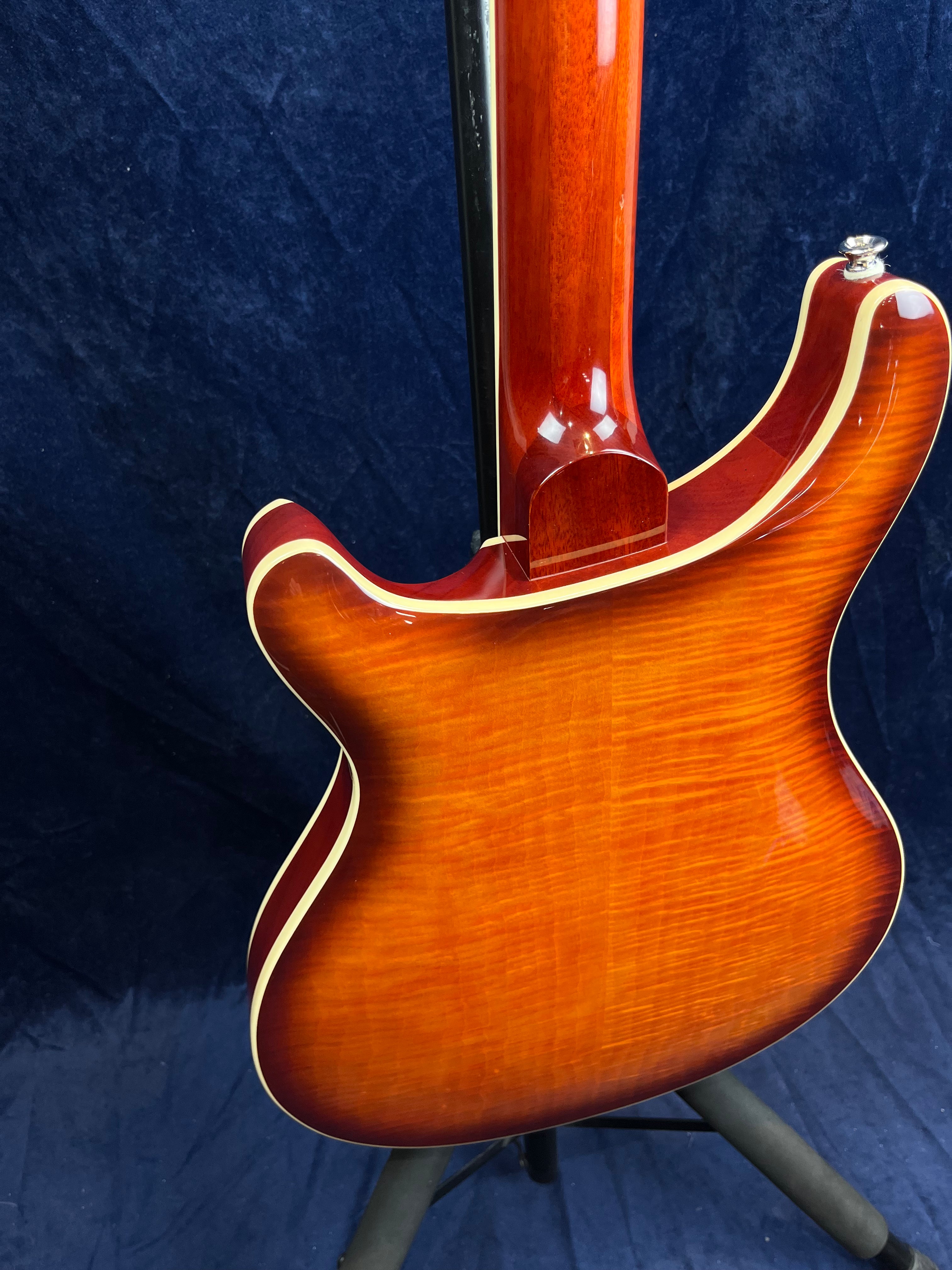 Glossy electric guitar with a sunburst orange and red finish, cream-colored binding, and visible wood grain on the back, shown against a dark background.