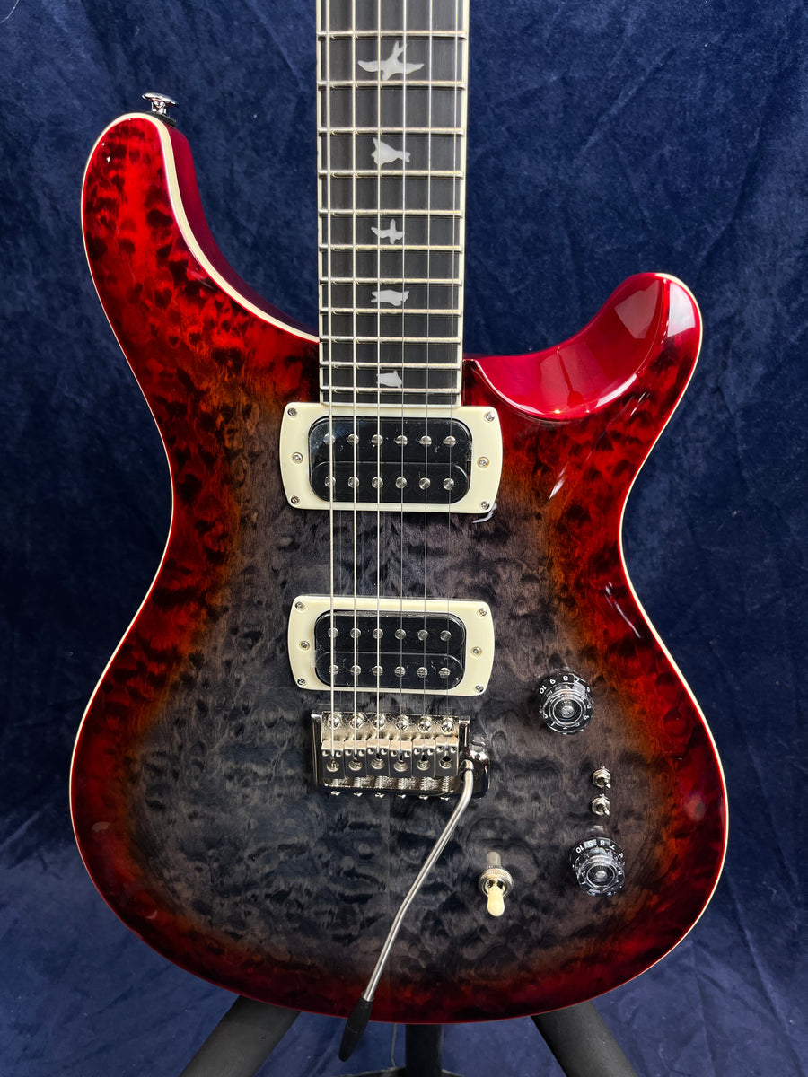 Electric guitar with a quilted red-to-black burst finish, two humbucker pickups, bird inlays on the fretboard, and a whammy bar.