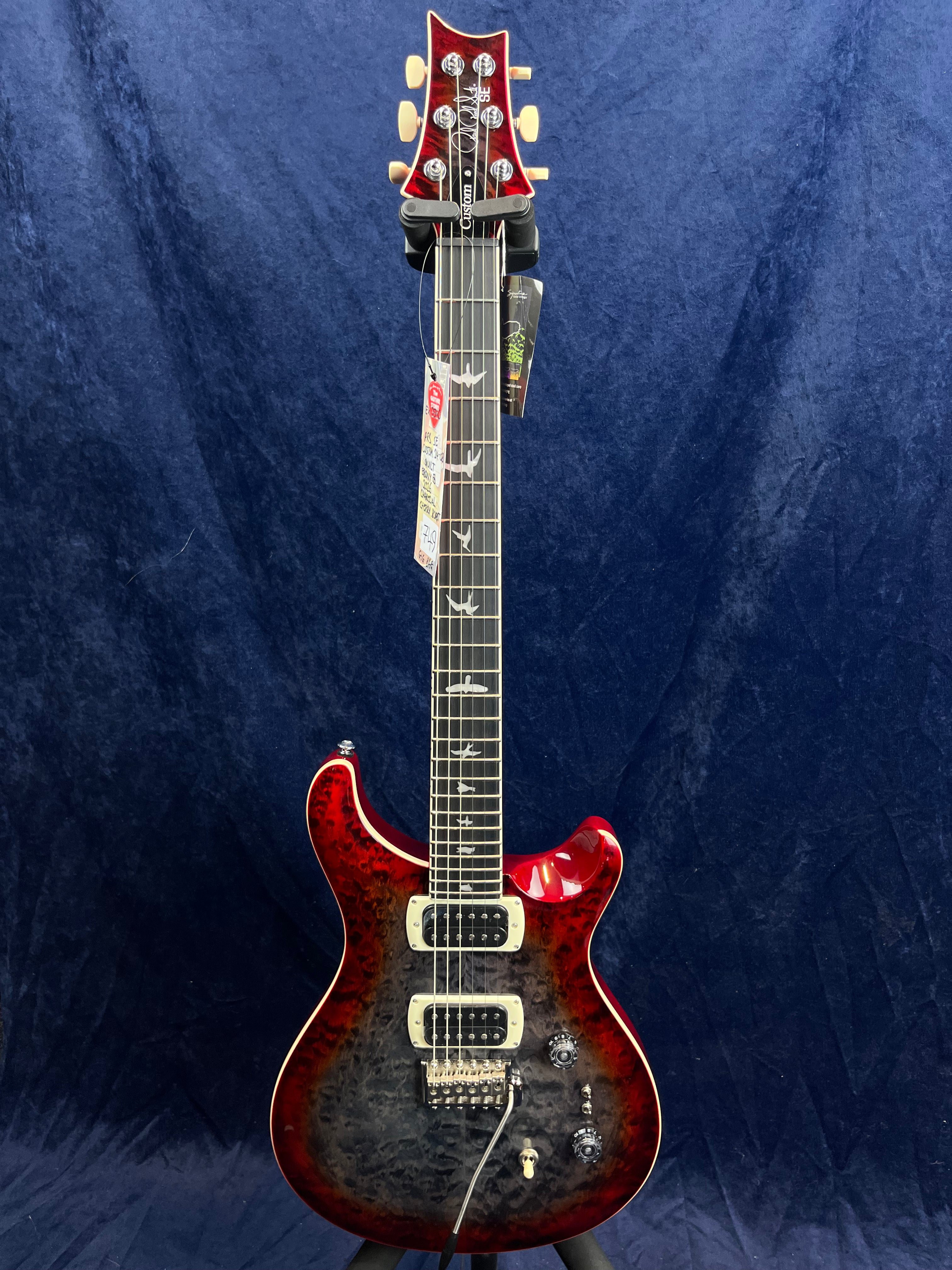 Electric guitar with a glossy red and black quilted finish, two humbucker pickups, bird inlays on the fretboard, and chrome hardware.