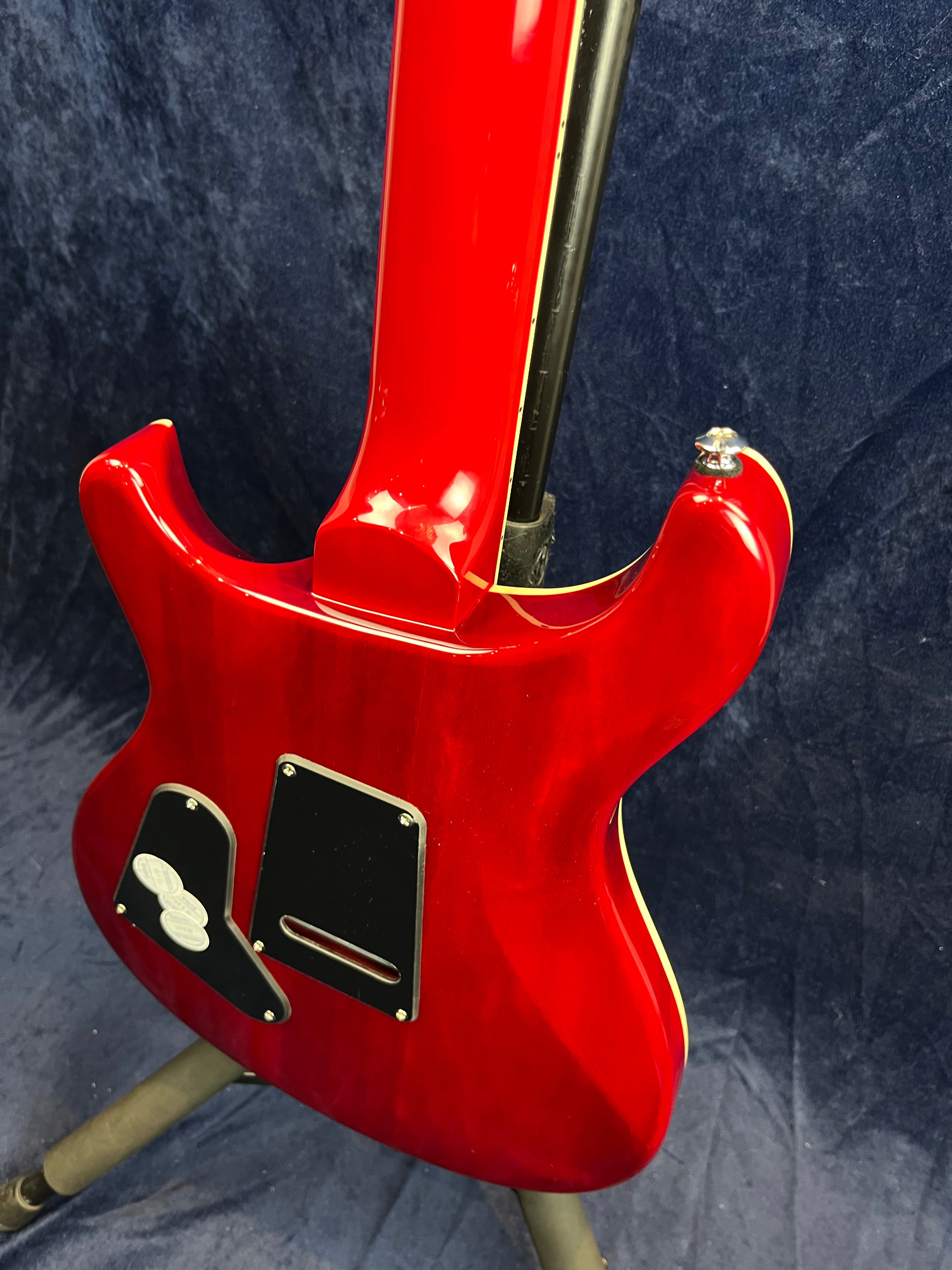 Red electric guitar shown from the back, featuring two black control cavity covers and cream binding along the body edge.