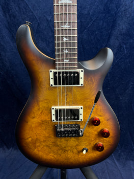 Glossy electric guitar with a dark burst finish, bird inlays on the fretboard, two humbucker pickups, three amber knobs, and a whammy bar.