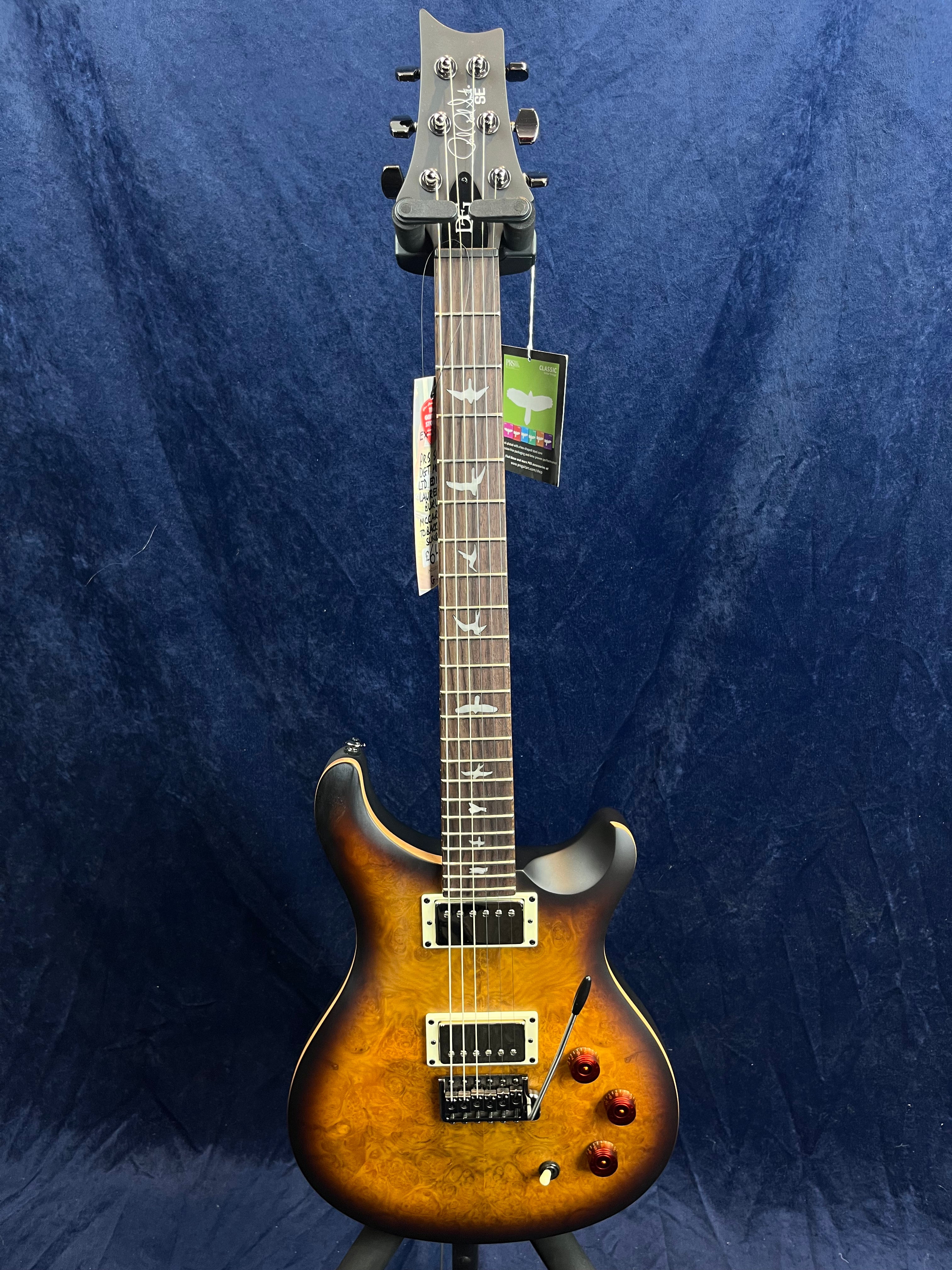 Sunburst finish electric guitar with a quilted maple top, two humbucker pickups, three amber control knobs, bird inlays on the fretboard, and a tremolo arm.
