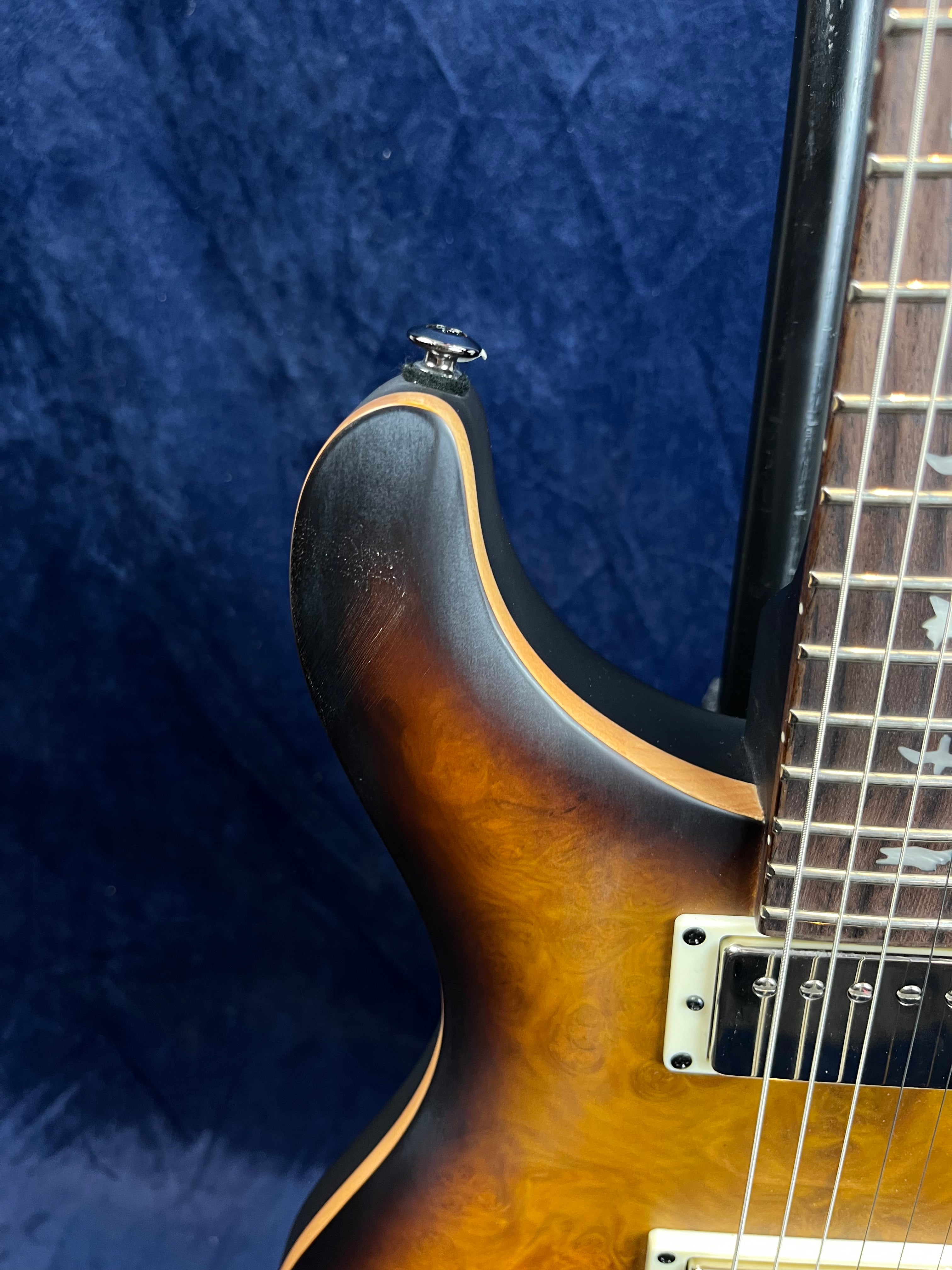 Upper body of an electric guitar with sunburst wood finish, cream-colored pickup frame, nickel hardware, and part of a rosewood fretboard.