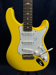 Bright yellow electric guitar with a white pickguard, three control knobs, a tremolo arm, and bird-shaped inlays on the dark fretboard.