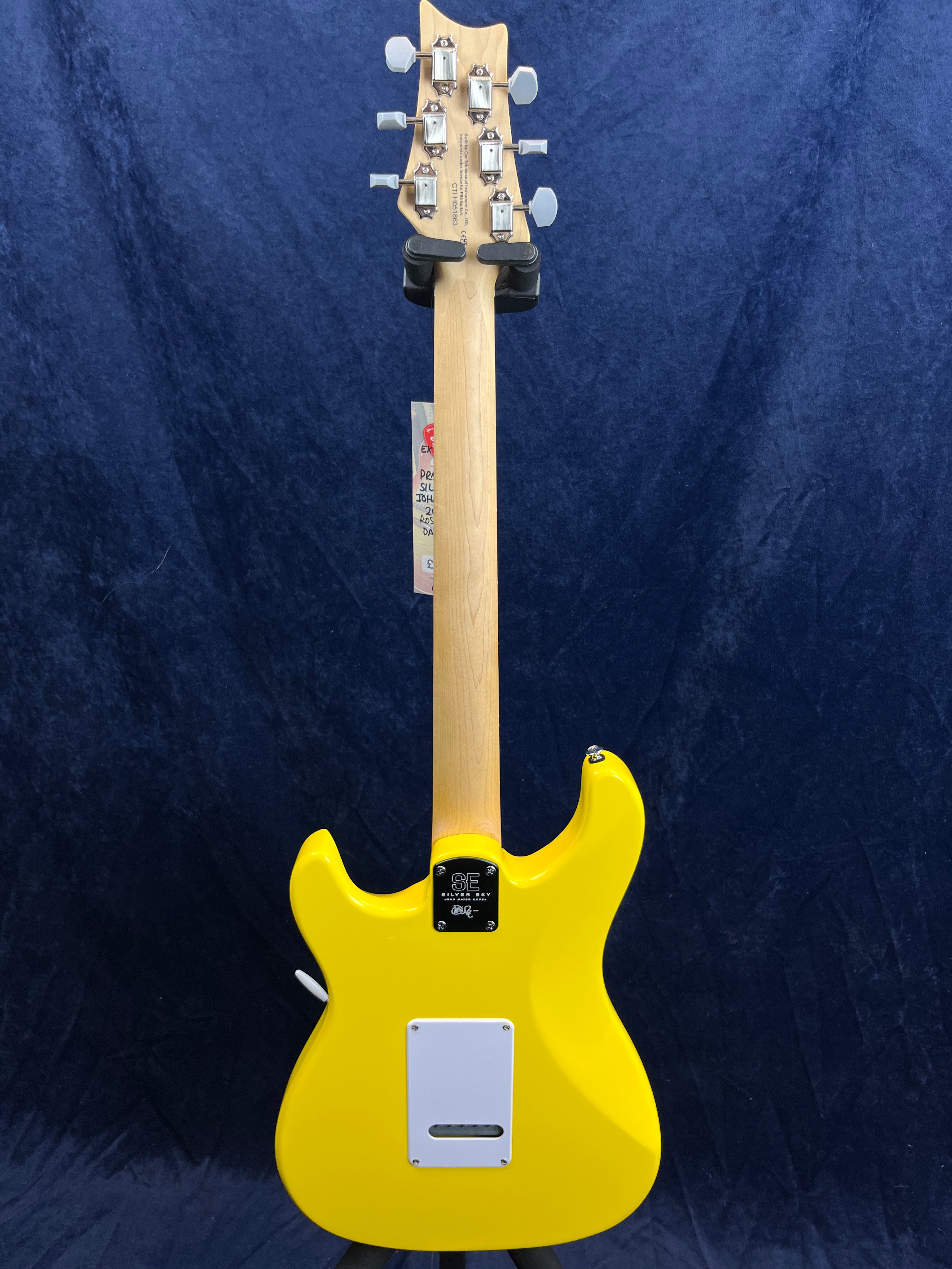 Bright yellow electric guitar shown from the back, natural wood neck, chrome tuners, white backplate, and a black neck joint plate with silver screws.