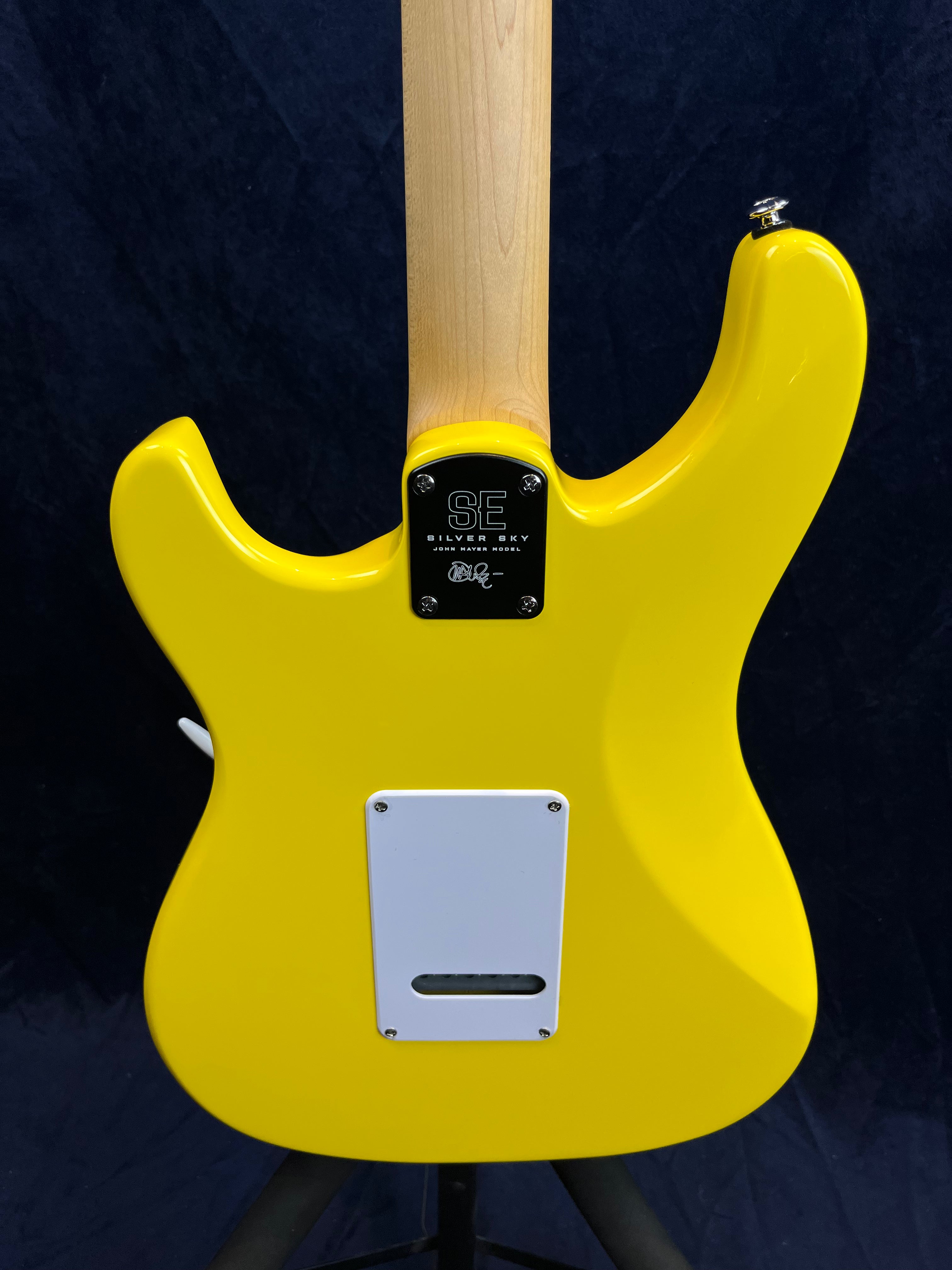 Bright yellow electric guitar back, natural wood neck, white plastic cover plate, metal neck plate labeled SE Silver Sky John Mayer Model.