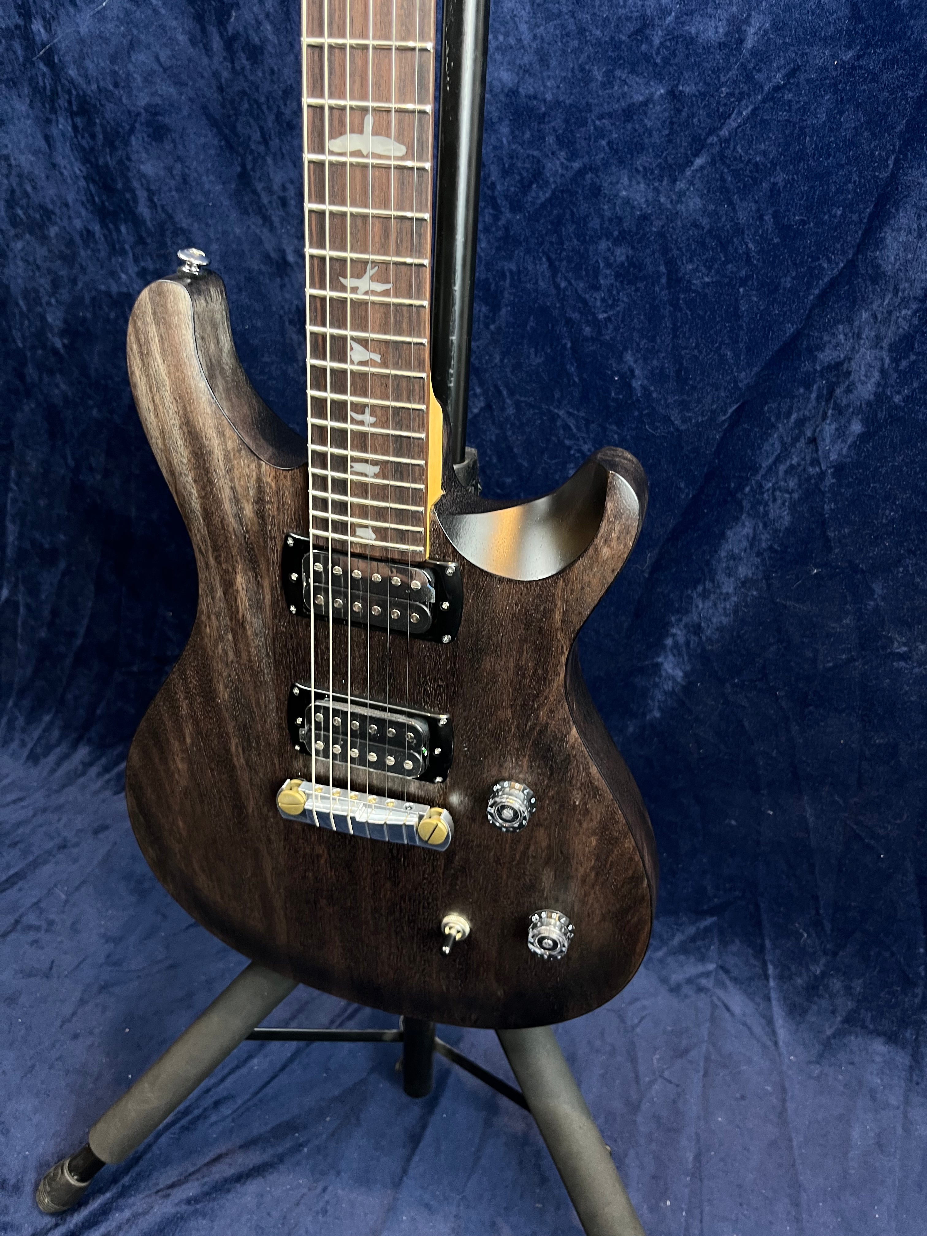Dark wood electric guitar with two humbucker pickups, bird inlays on the fretboard, two control knobs, and a three-way toggle switch.
