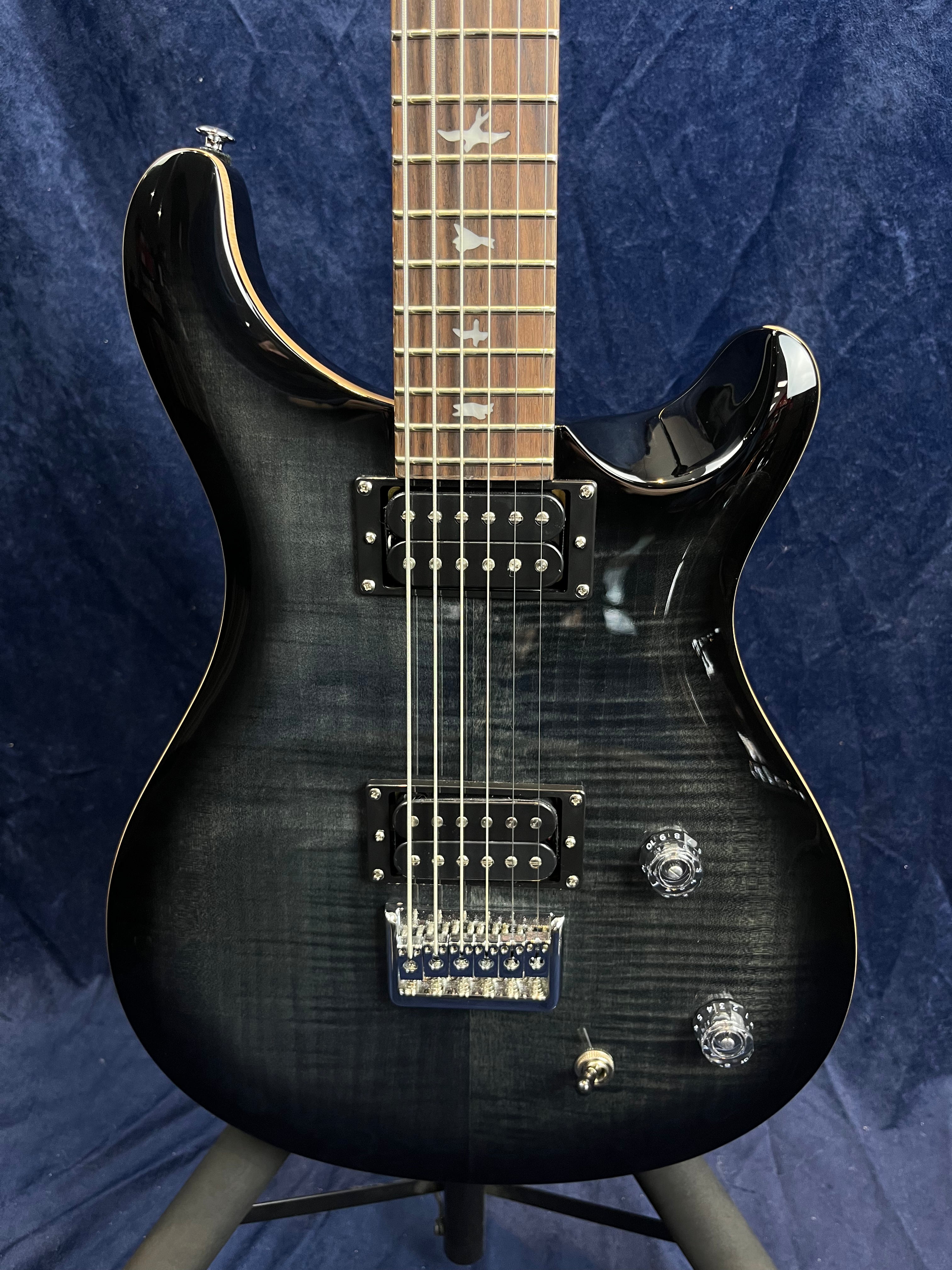 Black electric guitar with two humbucker pickups, two clear control knobs, a pickup selector switch, and bird inlays on the fretboard.