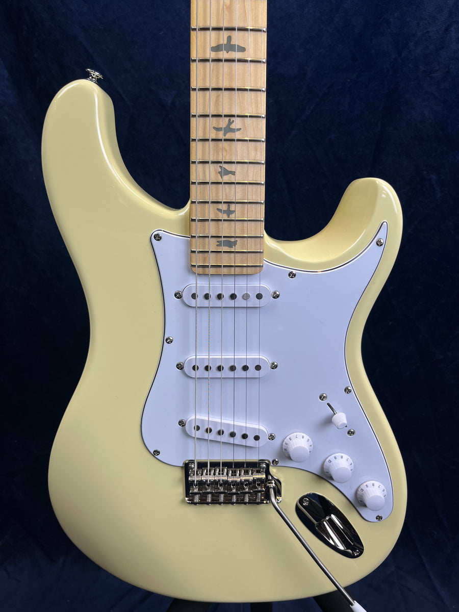 Cream-colored electric guitar with white pickguard, three single-coil pickups, three knobs, and maple neck featuring bird inlays on the fretboard.