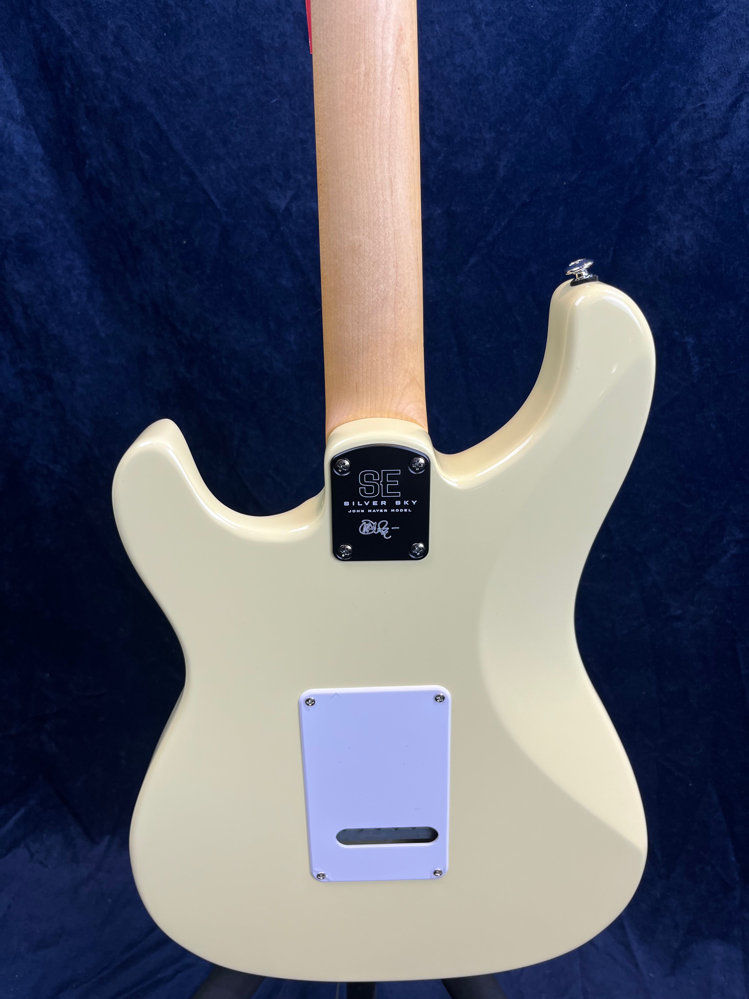 Cream-colored electric guitar back, natural wood neck, white plastic cover on body, metal plate marked SE Silver Sky near the neck joint.