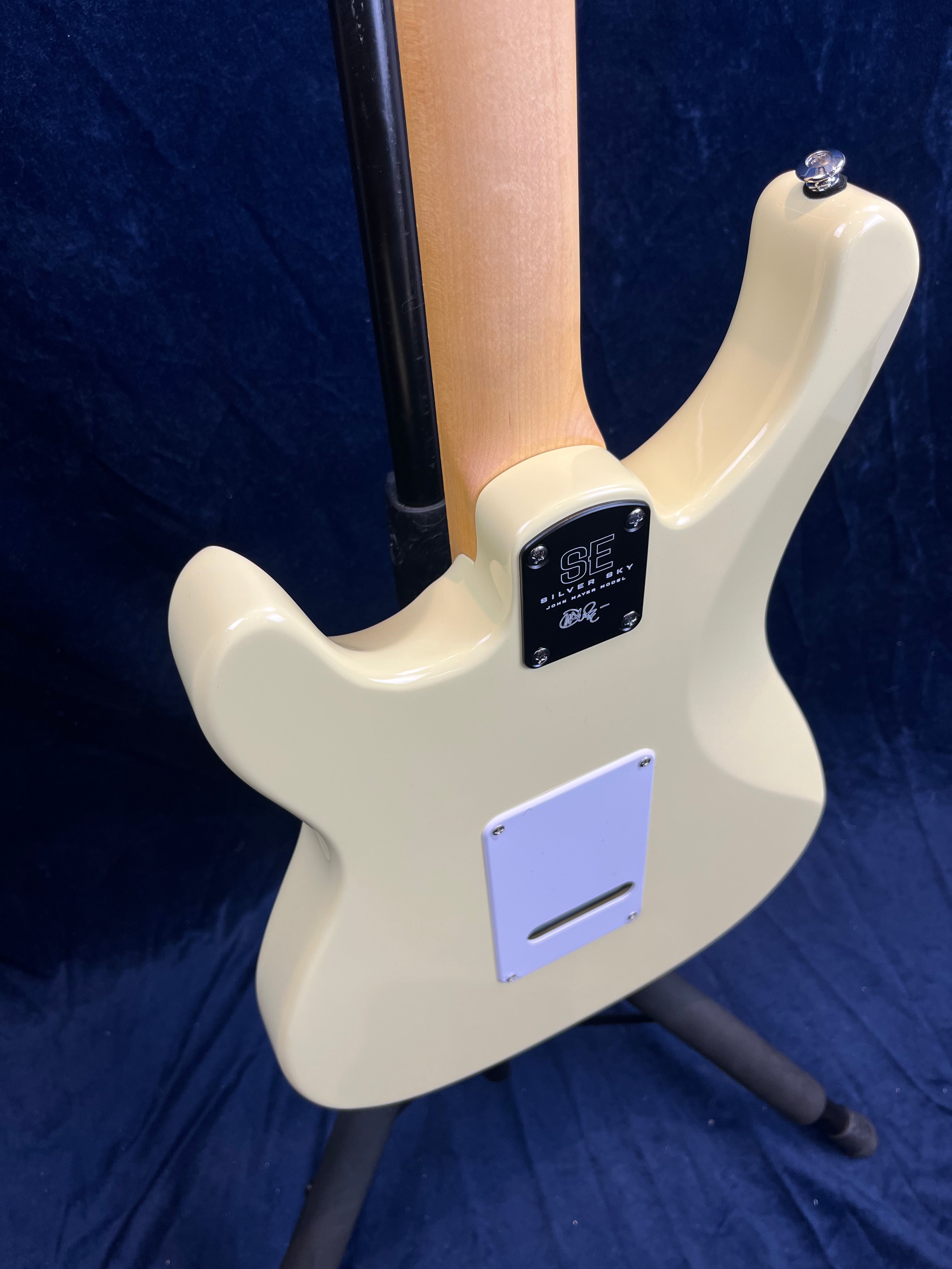 Cream-colored electric guitar shown from the back, light wood neck, metal neck plate labeled "SE Silver Sky," and a white rectangular back plate.