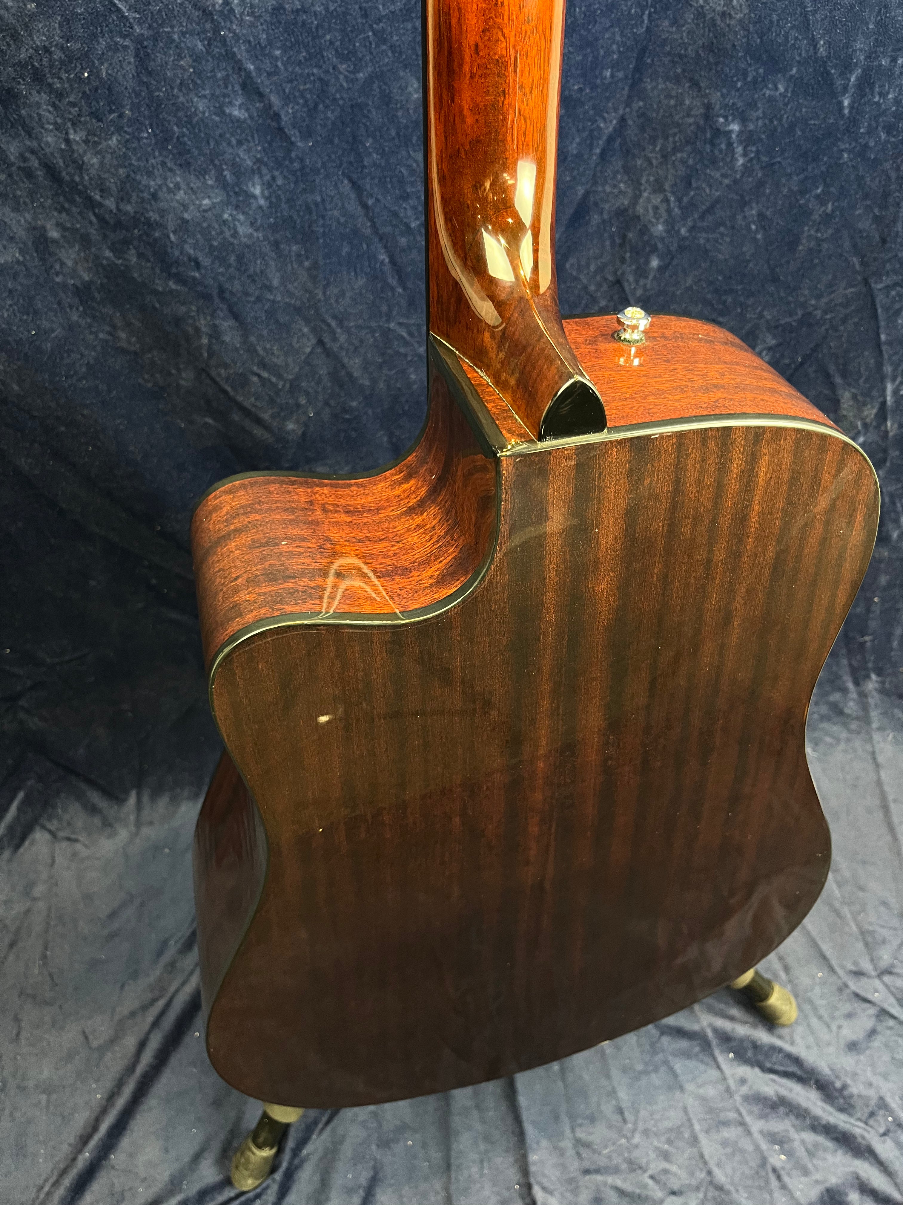 Dark wood acoustic guitar back and neck with a glossy finish, single strap button, small ding on the body, and black binding.