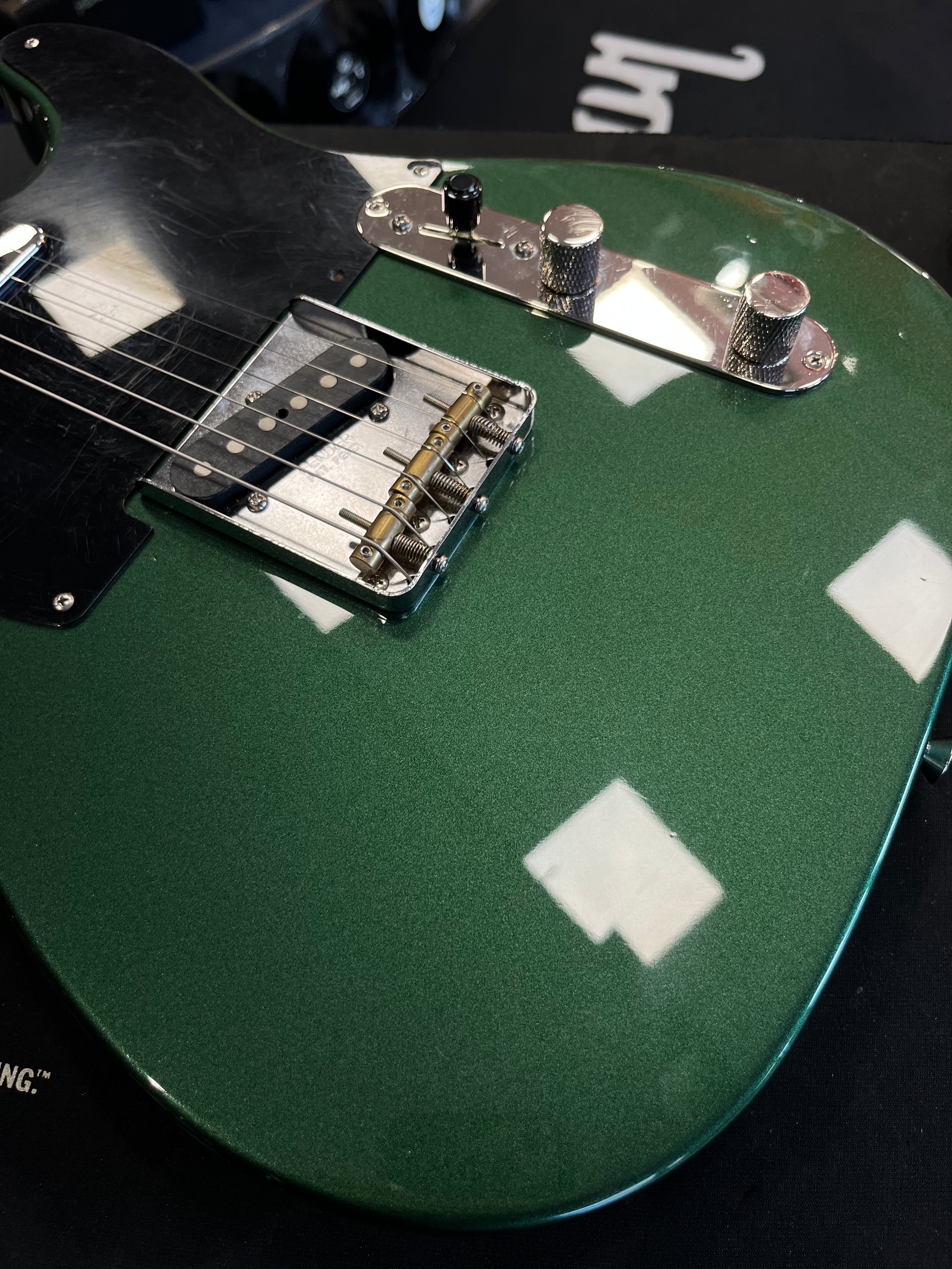Green electric guitar with silver knobs, a black pickguard, and two white paint patches on the lower body.