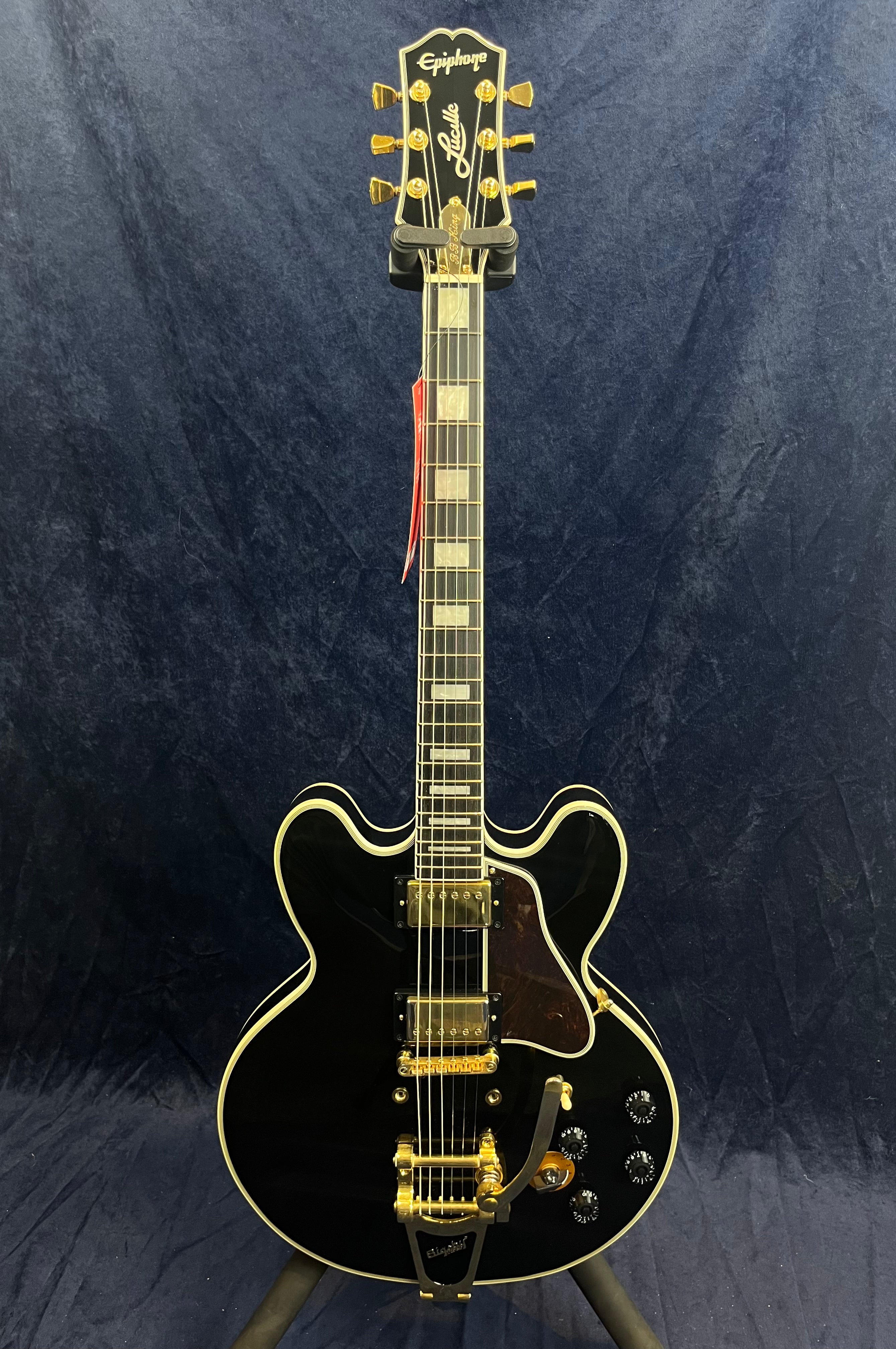 Black Epiphone semi-hollow electric guitar with gold hardware, double cutaway body, Bigsby vibrato tailpiece, and block inlays on the fretboard.