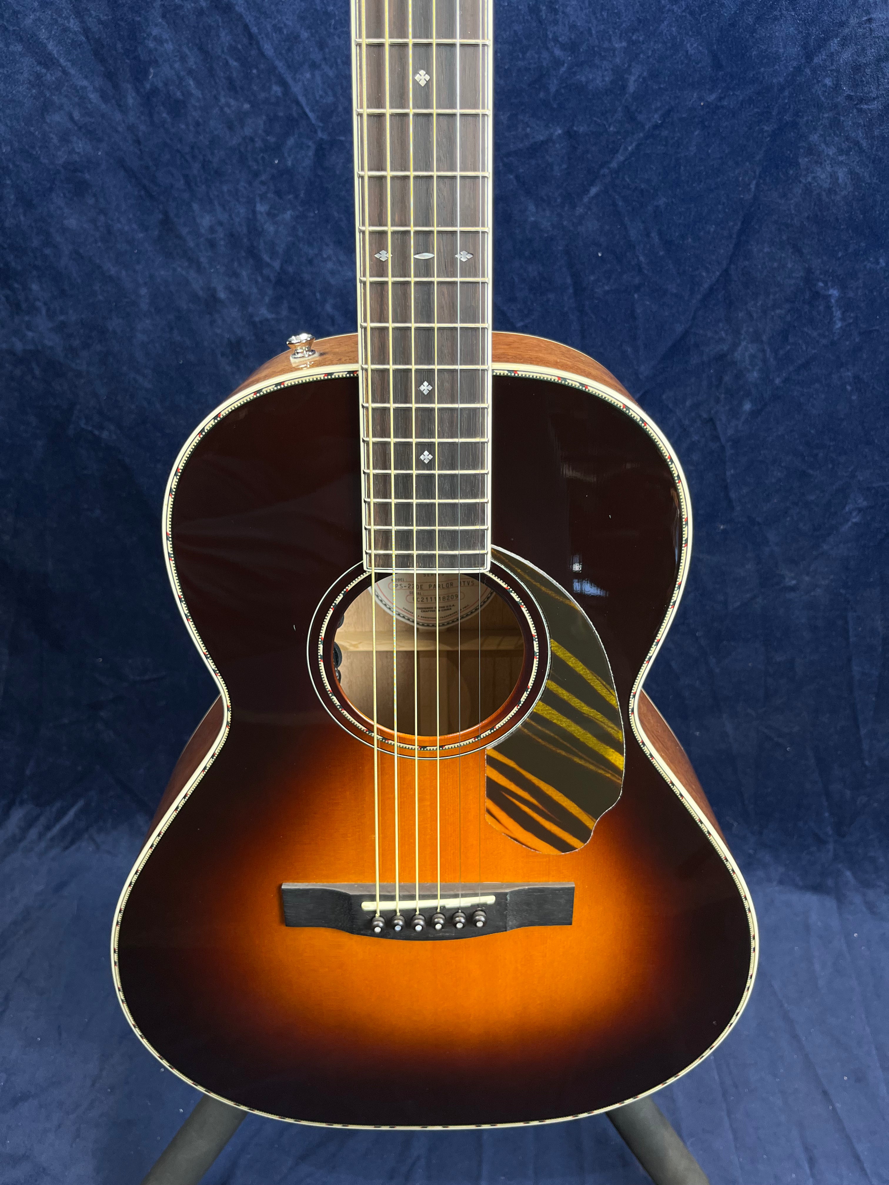 Sunburst acoustic guitar with a decorative pickguard featuring yellow stripes, diamond inlays on the fretboard, and light trim around the body.