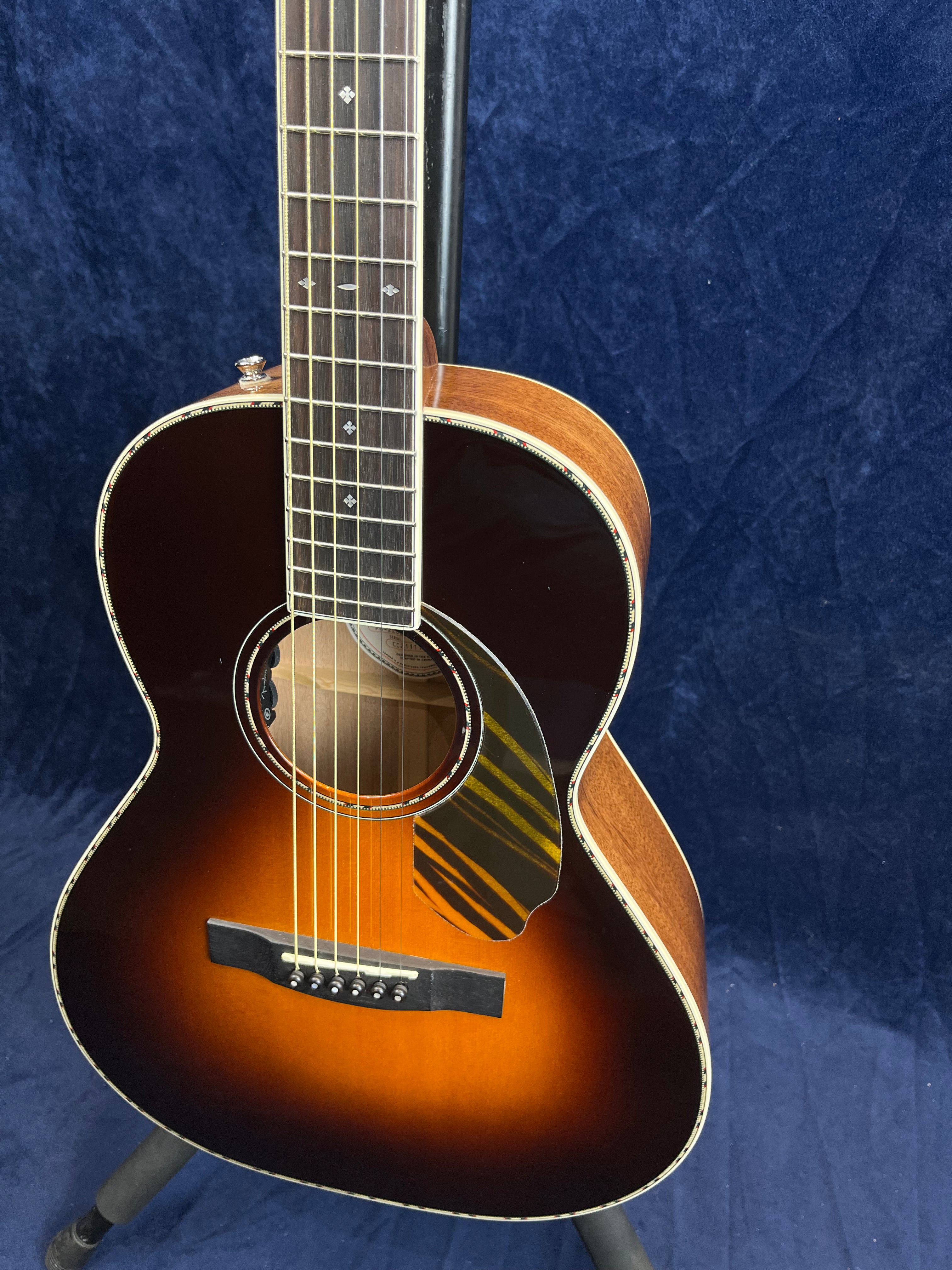 Sunburst acoustic guitar with a decorated soundhole, striped black and yellow pickguard, light wood sides, and patterned fretboard inlays.