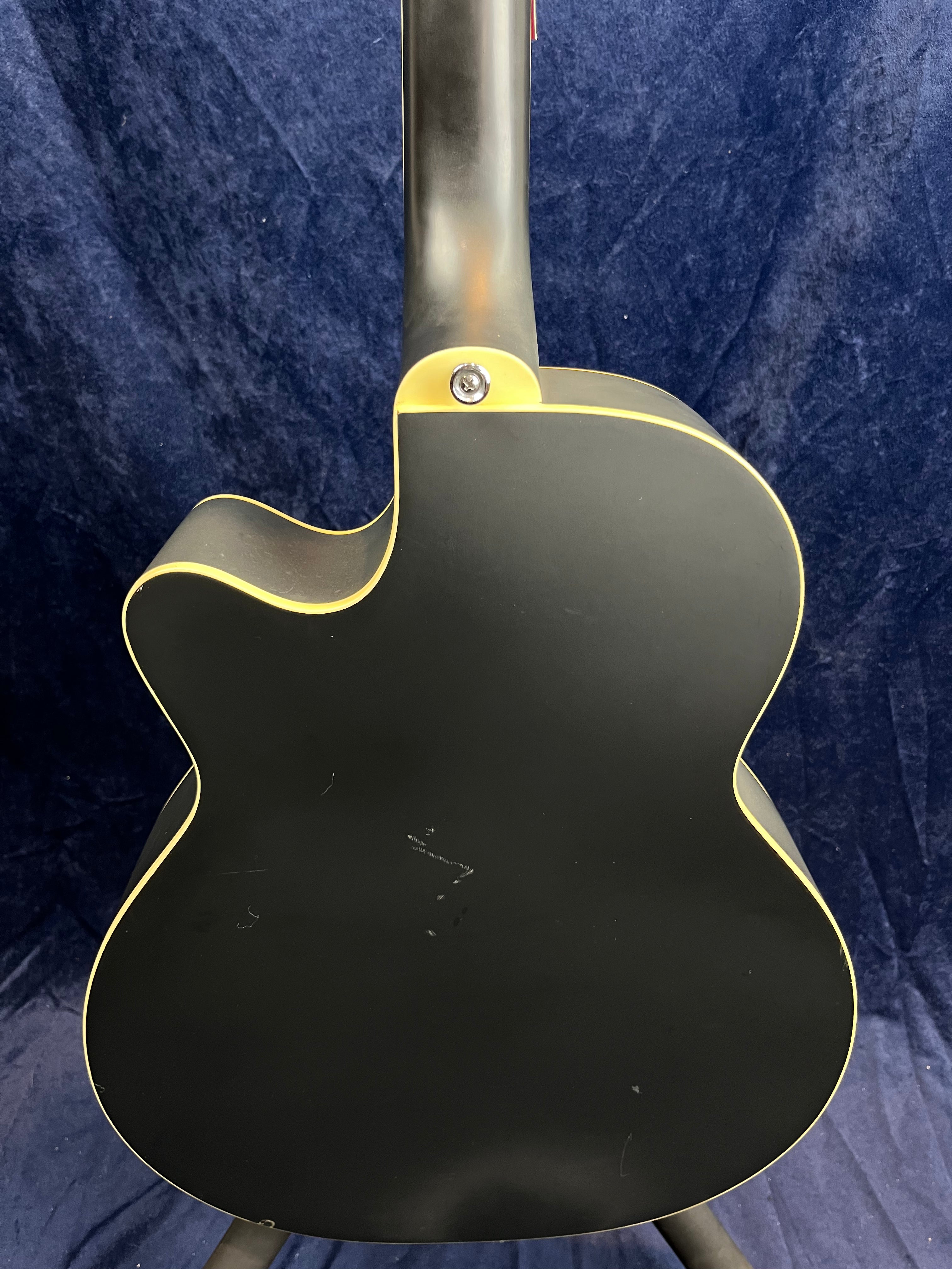 The back of a matte black electric guitar with cream binding, single cutaway design, and a bolt-on neck joint. Some light scratches are visible.