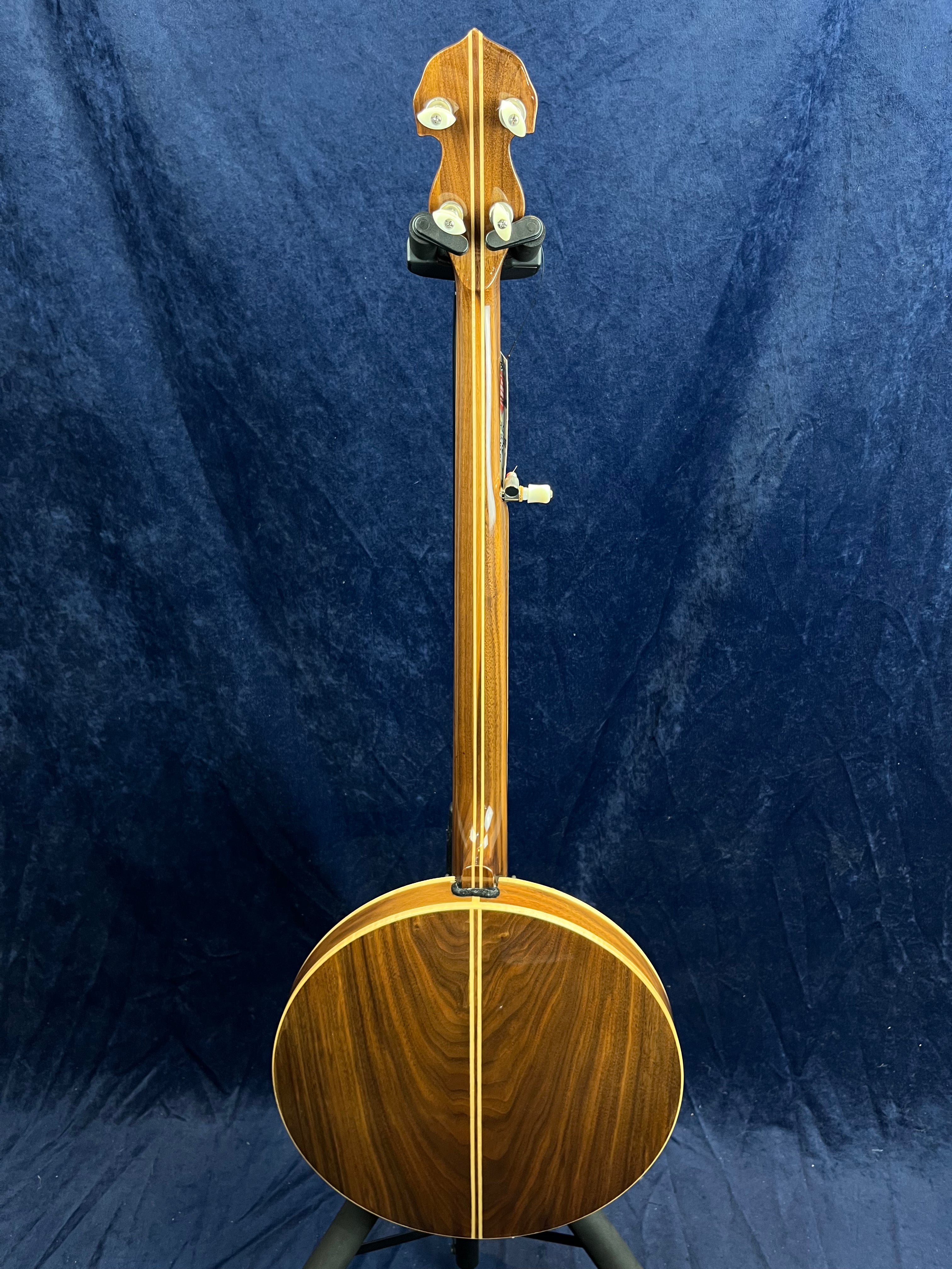 Banjo vu de dos, entièrement en bois verni, avec une caisse ronde et un manche droit, quatre mécaniques de réglage sur la tête.