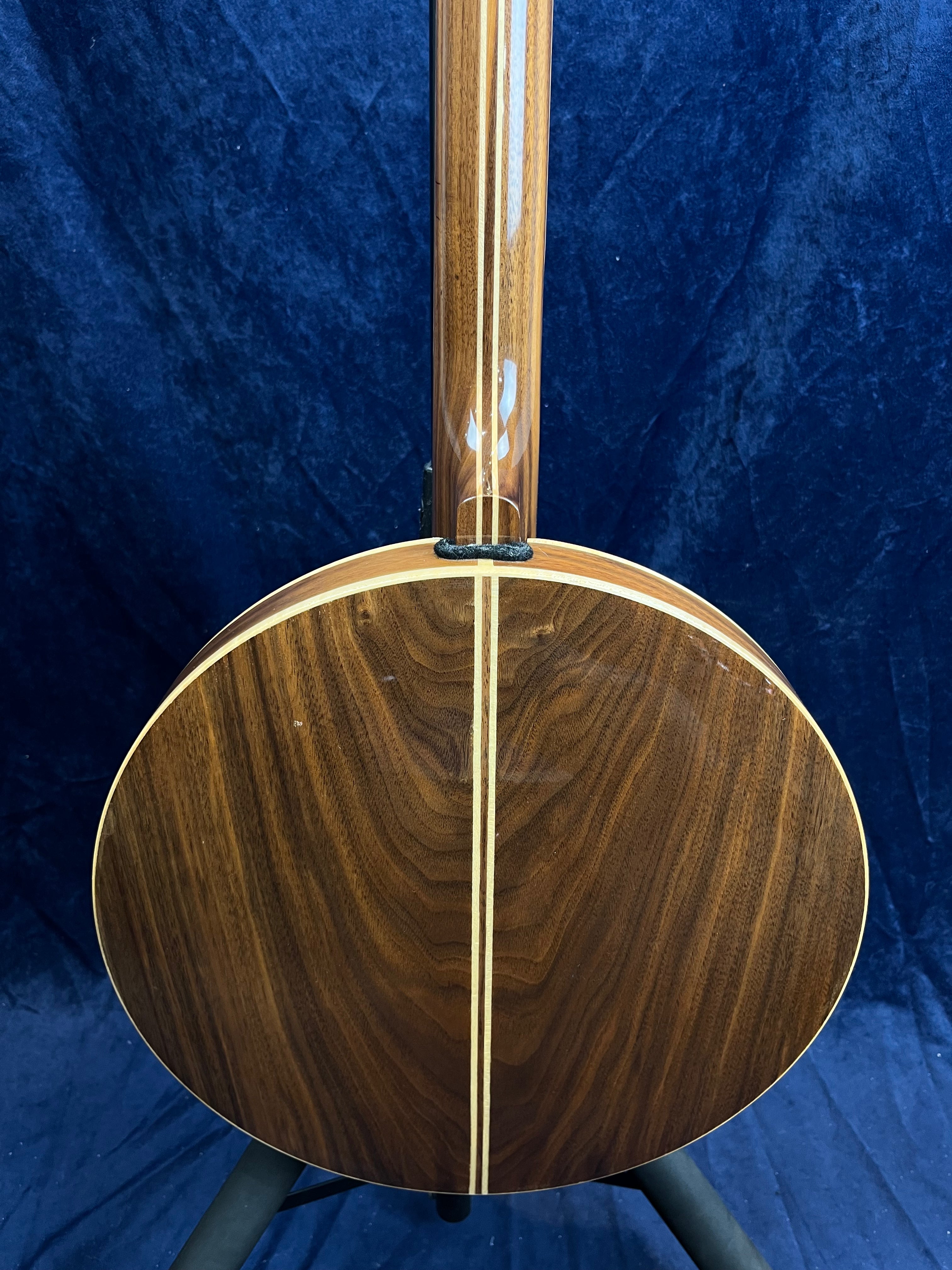 Banjo vu de dos, bois foncé verni aux motifs naturels, avec deux bandes claires verticales au centre de la caisse et du manche.