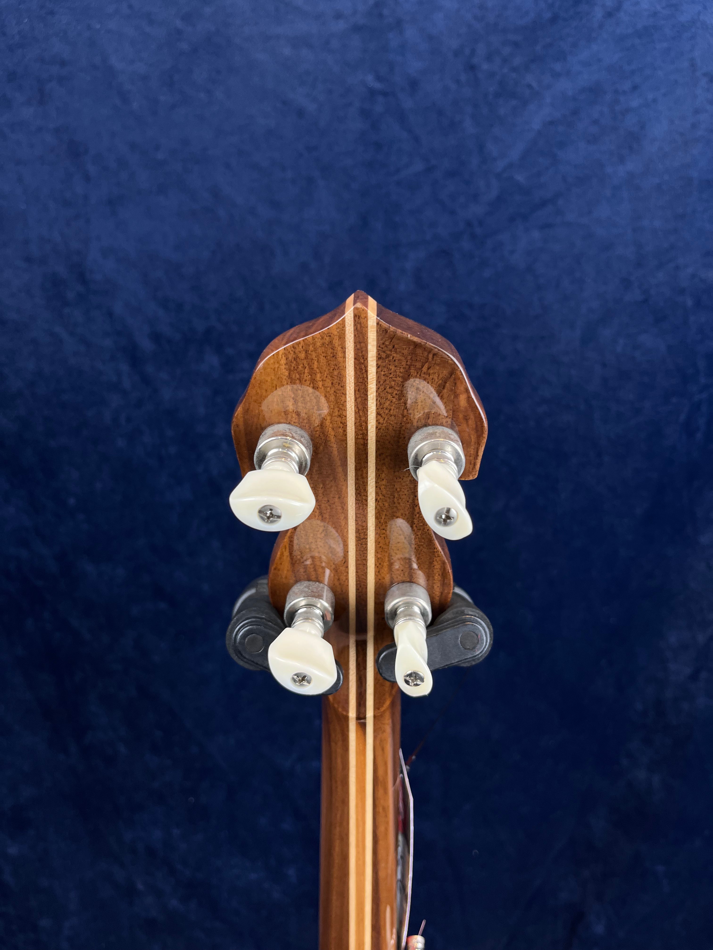 Tête de banjo en bois verni à motif central, vue de dos, avec quatre mécaniques à boutons blancs alignées par paires.