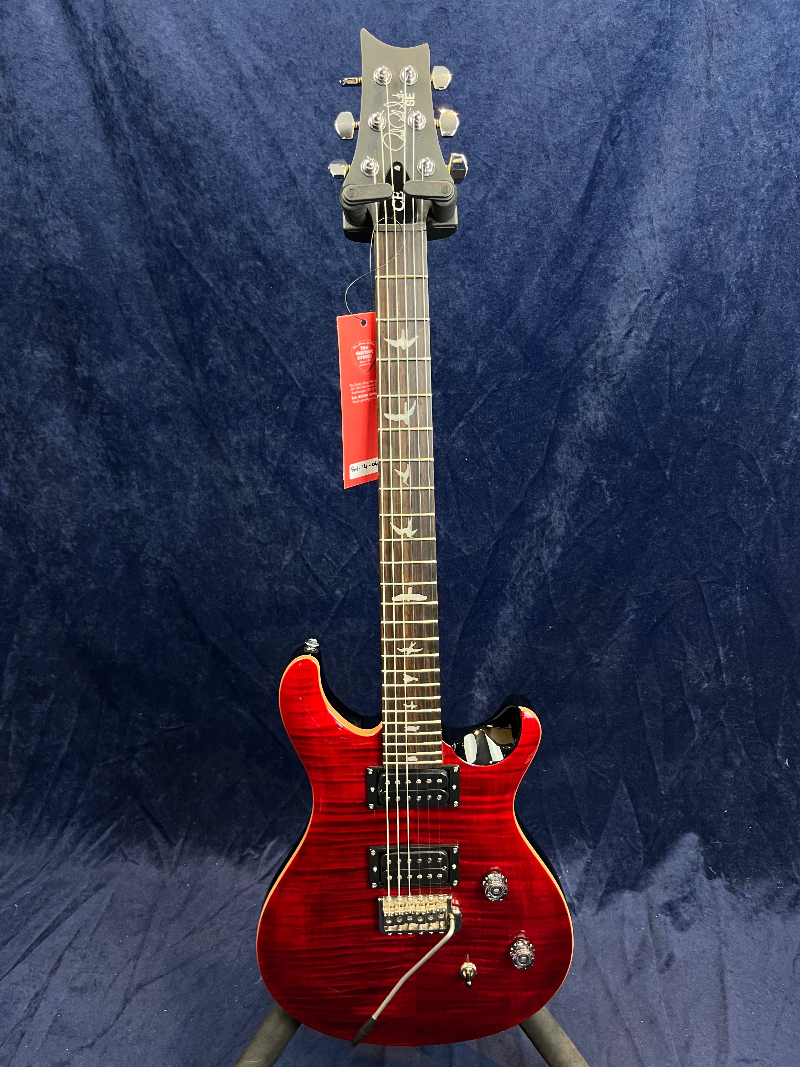 Guitare électrique rouge brillant à deux micros doubles, manche orné d’incrustations en forme d’oiseaux, sélecteur et deux boutons de réglage.