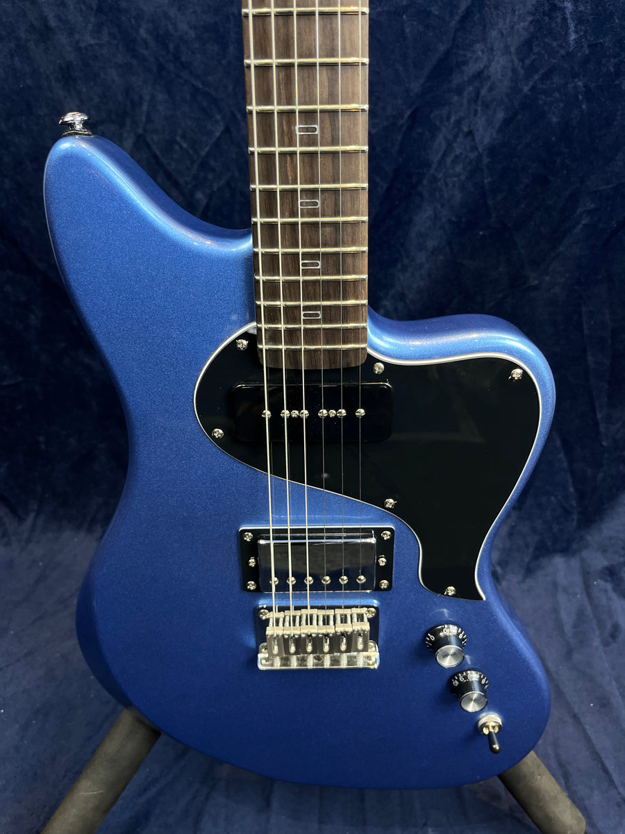 Metallic blue electric guitar with black pickguard, two pickups, three control knobs, and a chrome bridge against a dark background.